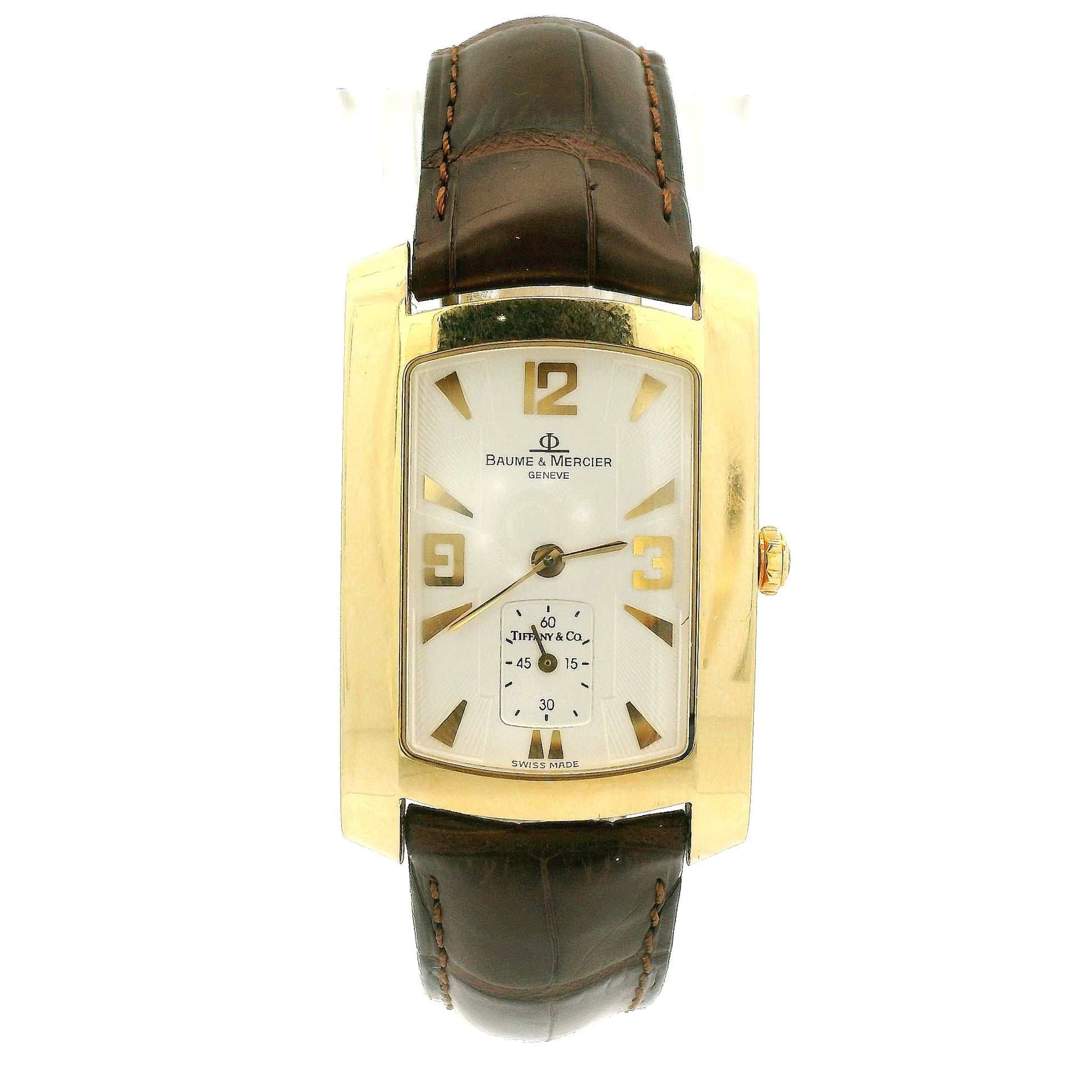 A Vintage Baume & Mercier watch with a 18k gold rectangular case, cream dial with 9, 12 & 3 displayed, the dial is stamped with a tiffany & Co., and dark brown leather strap, shown against a plain white background at Forever Rox Fine Jewelry, Lake Tahoes Best Jewelry Store