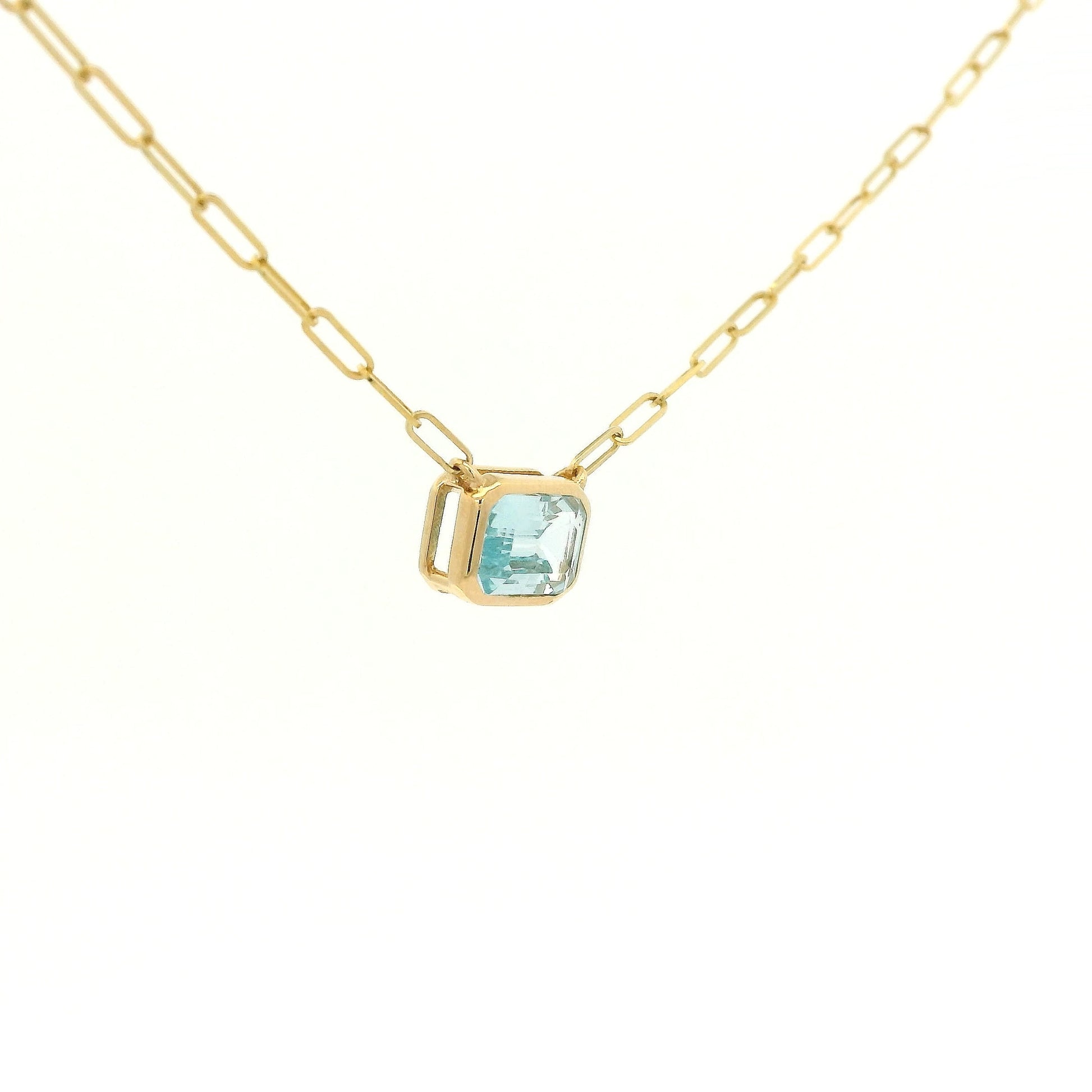 A Yellow Gold Pendant with a bezel set emerald cut natural Swiss Blue Topaz in the center with a paperclip chain attached at Forever Rox Fine Jewelry, Lake Tahoes Best Jewelry Store
