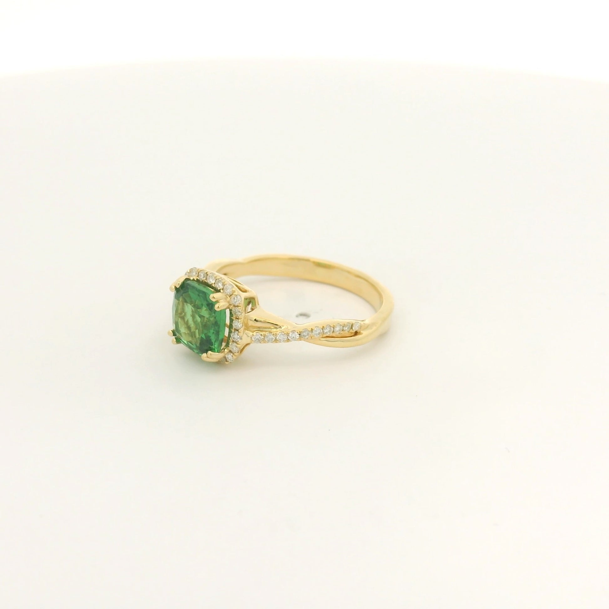 A Yellow Gold Crossover Ring with a prong set cushion cut natural Tsavorite in the center with a halo of diamonds and diamonds down shank at Forever Rox Fine Jewelry, Lake Tahoes Best Jewelry Store