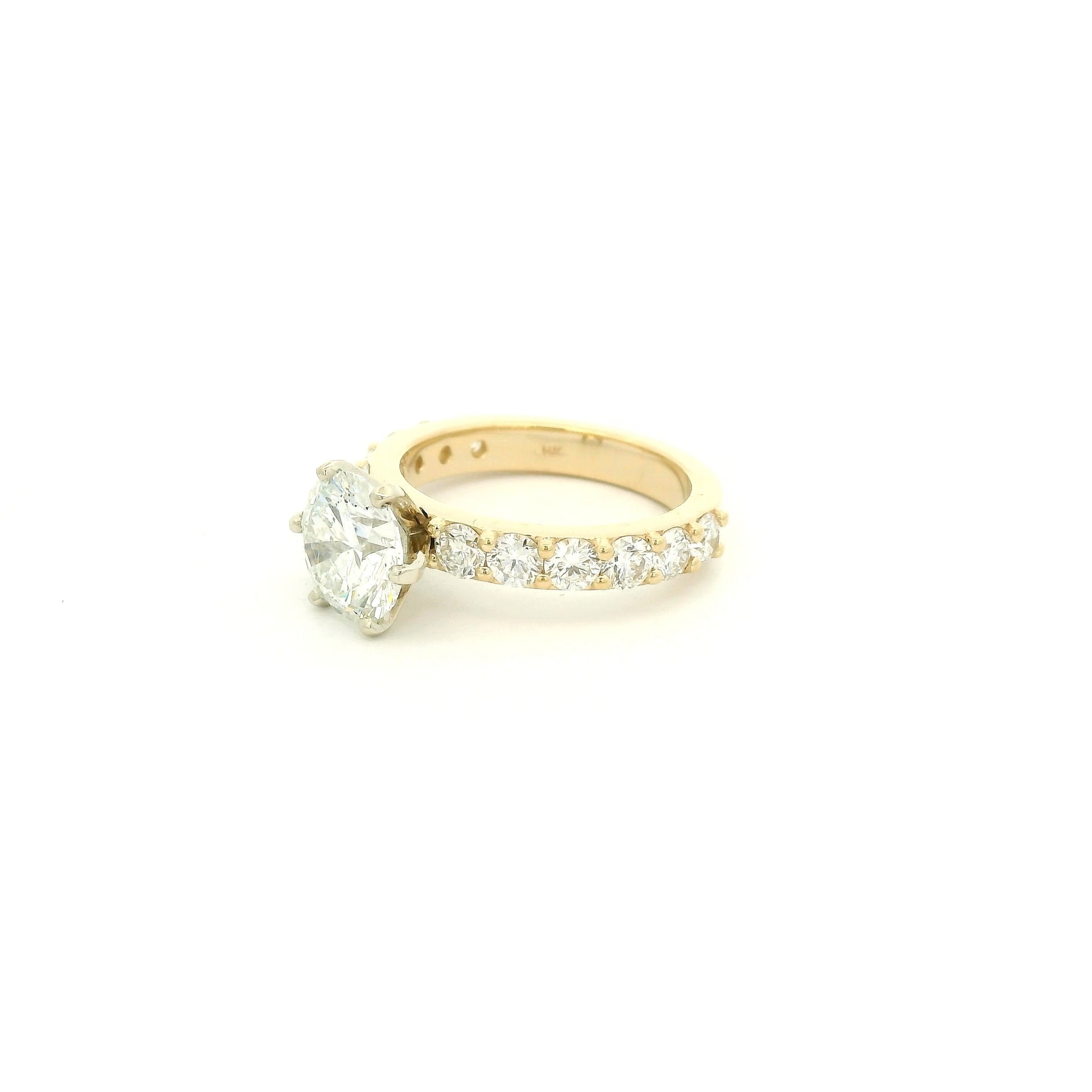 This custom 14k yellow gold engagement ring was designed around a client’s treasured diamond, creating a one-of-a-kind heirloom to be cherished for generations. The stunning 2.05 carat round brilliant cut natural diamond was professionally GIA graded as F color, VS1 clarity, and Excellent cut, polish, and symmetry (Triple Excellent) before being set into its custom-made mounting. Framing the center stone are 1.30 total carats of natural diamonds flowing down the substantial 3mm-wide band, adding brilliance 