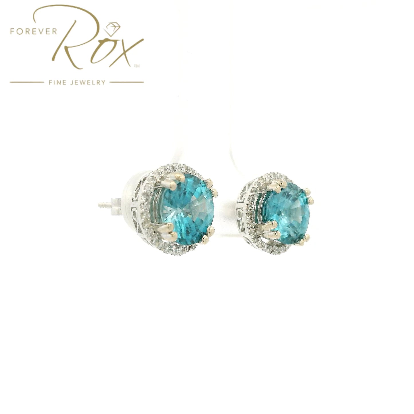 A Pair of White Gold Earrings with prong set round cut natural Blue Zircon in the center with a diamond halo at Forever Rox Fine Jewelry, Lake Tahoes Best Jewelry Store