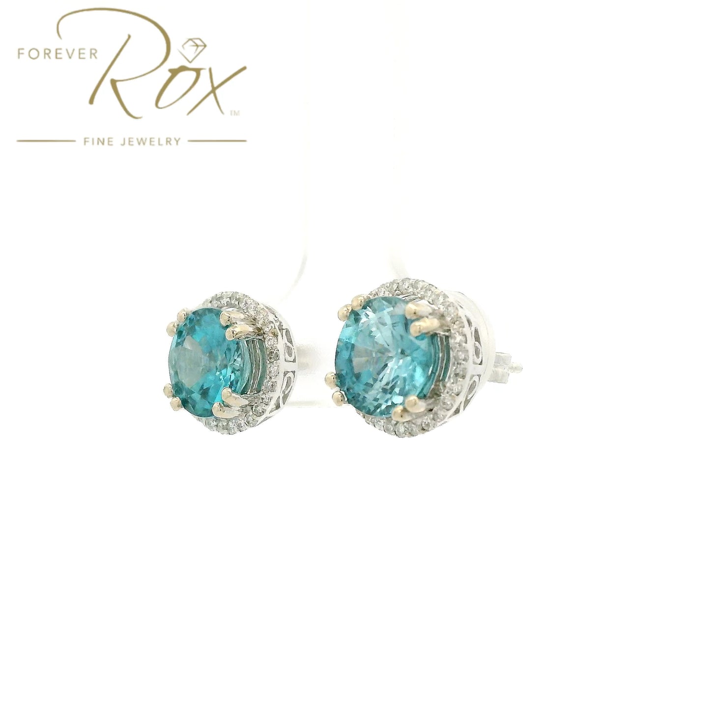 A Pair of White Gold Earrings with prong set round cut natural Blue Zircon in the center with a diamond halo at Forever Rox Fine Jewelry, Lake Tahoes Best Jewelry Store