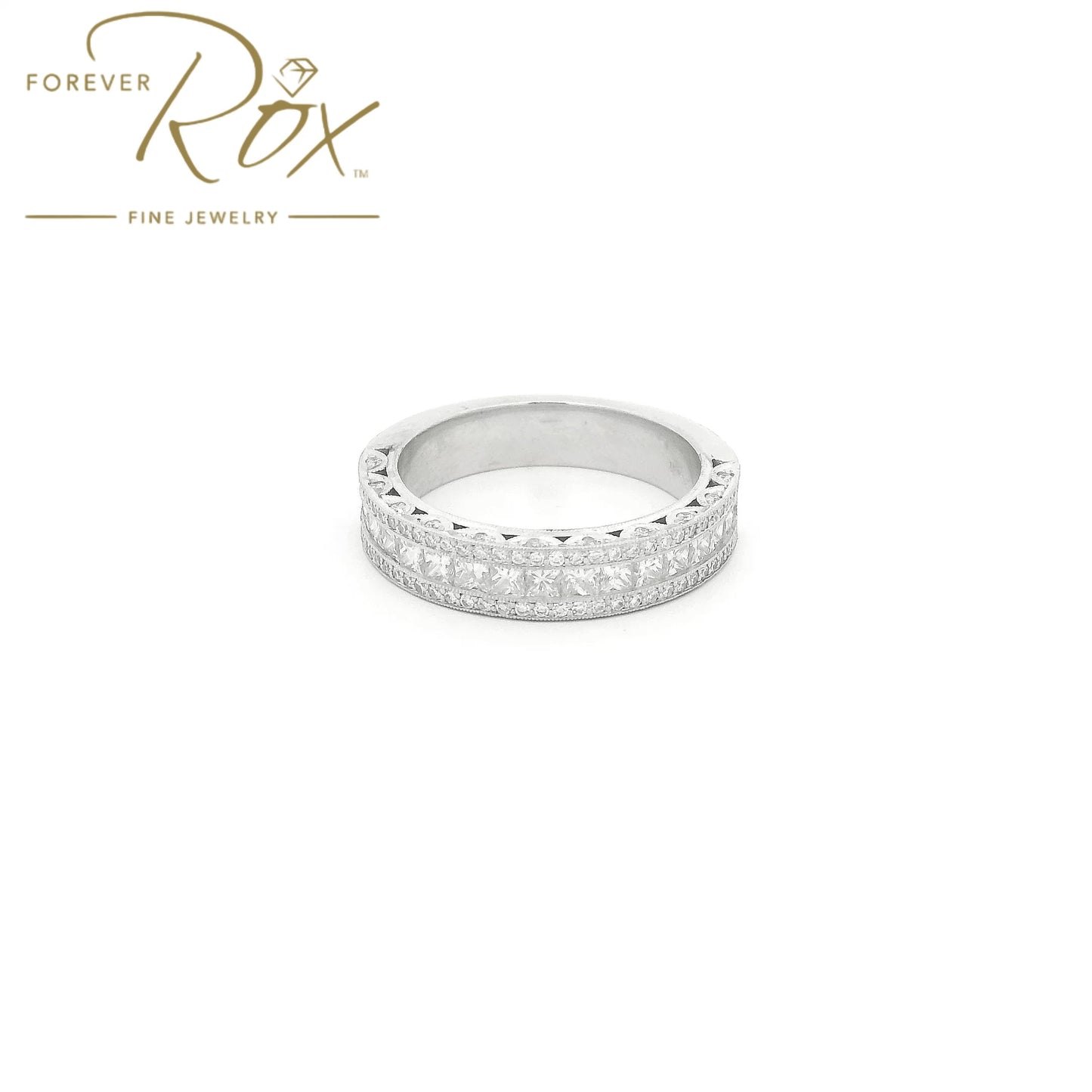 This custom 14k white gold diamond band was designed to perfectly complement a client’s original ring that we previously created for her. The center features a row of channel-set princess-cut diamonds, framed above and below by channel-set round brilliant diamonds for added sparkle. Intricate filigree detailing along the edges was carefully incorporated to match the design of her original ring, creating a cohesive, one-of-a-kind set made especially for her.