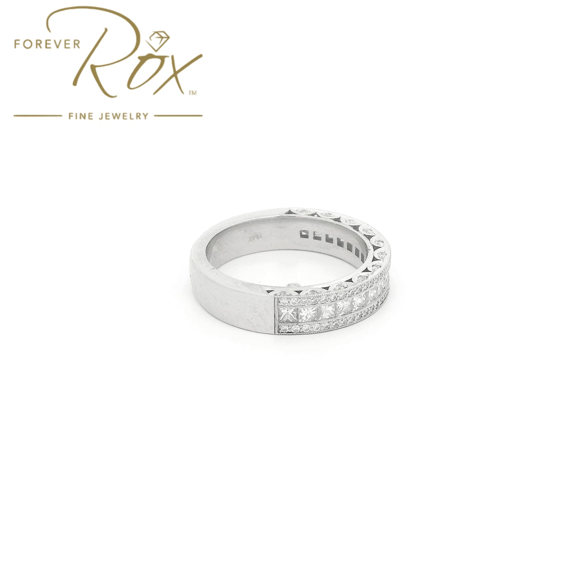This custom platinum diamond band was designed to perfectly complement a client’s original ring that we previously created for her. The center features a row of channel-set princess-cut diamonds, framed above and below by channel-set round brilliant diamonds for added sparkle. Intricate filigree detailing along the edges was carefully incorporated to match the design of her original ring, creating a cohesive, one-of-a-kind set made especially for her.