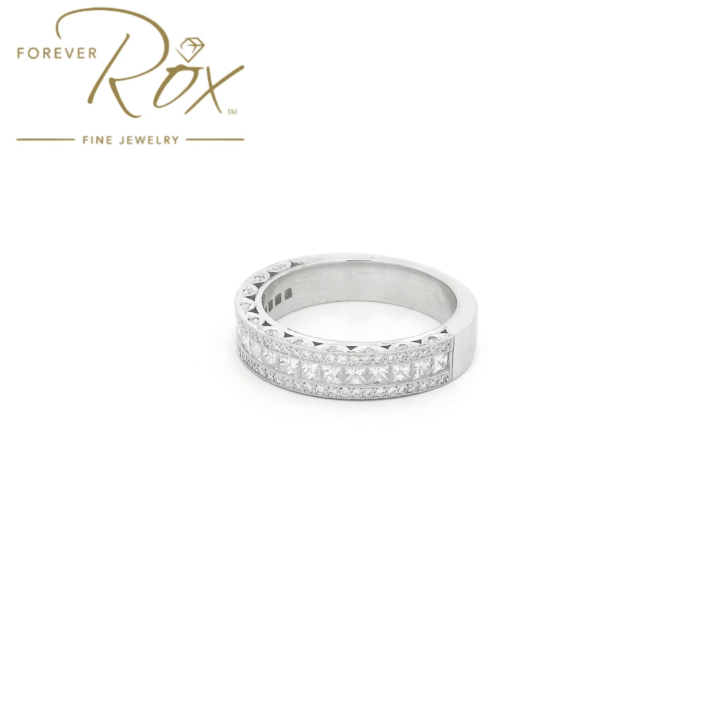 This custom platinum diamond band was designed to perfectly complement a client’s original ring that we previously created for her. The center features a row of channel-set princess-cut diamonds, framed above and below by channel-set round brilliant diamonds for added sparkle. Intricate filigree detailing along the edges was carefully incorporated to match the design of her original ring, creating a cohesive, one-of-a-kind set made especially for her.