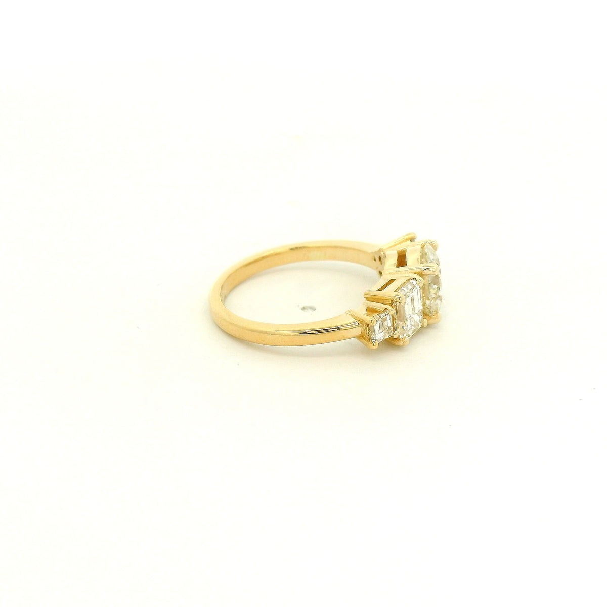 This custom 14k yellow gold engagement ring features a 1.53 ct H-VS2 round brilliant diamond accented by an asymmetrical arrangement of mixed-cut natural diamonds, including a .70 ct F-VVS2 emerald cut, .15 ct G-VS2 pear cut, .17 ct square emerald cut, and two smaller round diamonds. 