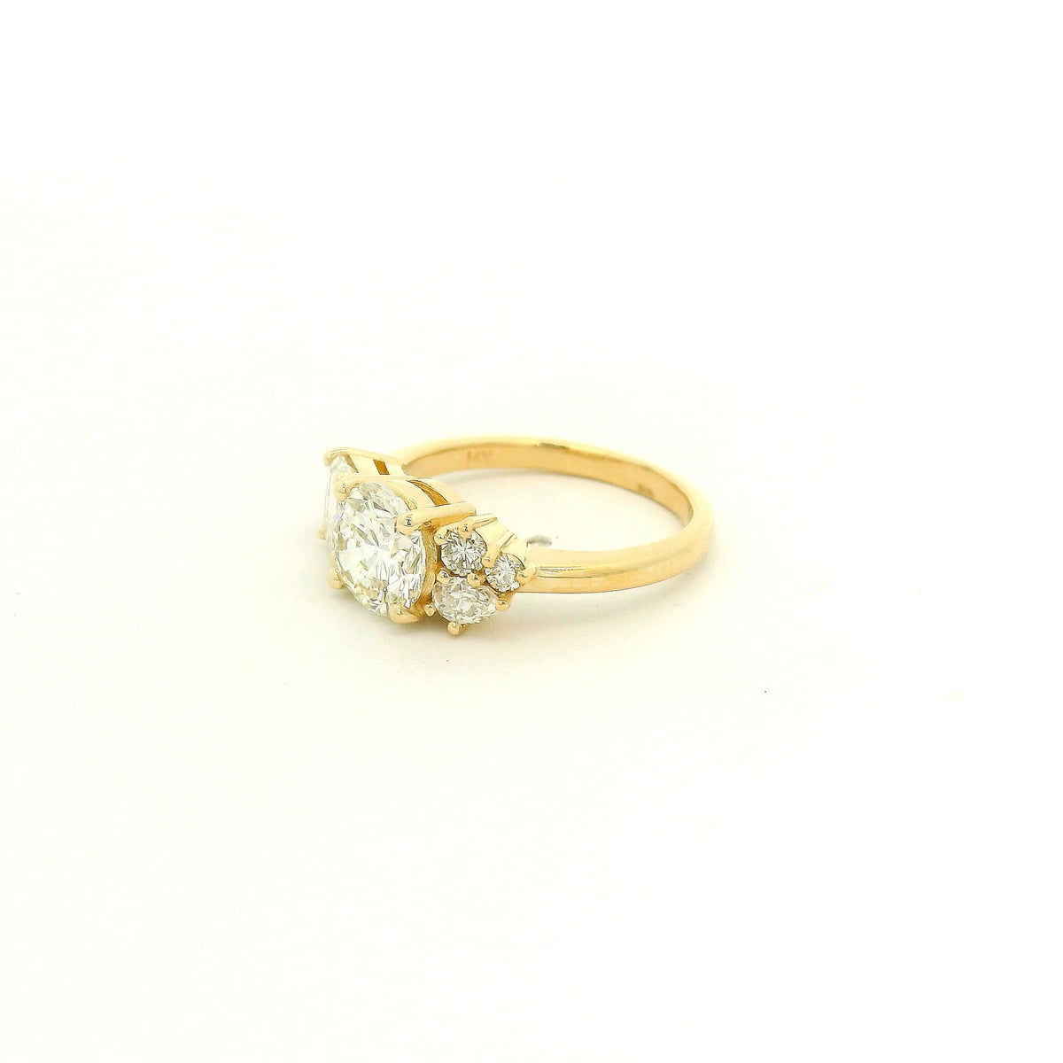 This custom 14k yellow gold engagement ring features a 1.53 ct H-VS2 round brilliant diamond accented by an asymmetrical arrangement of mixed-cut natural diamonds, including a .70 ct F-VVS2 emerald cut, .15 ct G-VS2 pear cut, .17 ct square emerald cut, and two smaller round diamonds. 