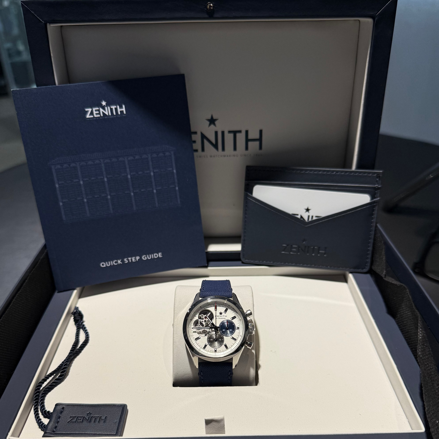Zenith watch in a display case with packaging and accessories.