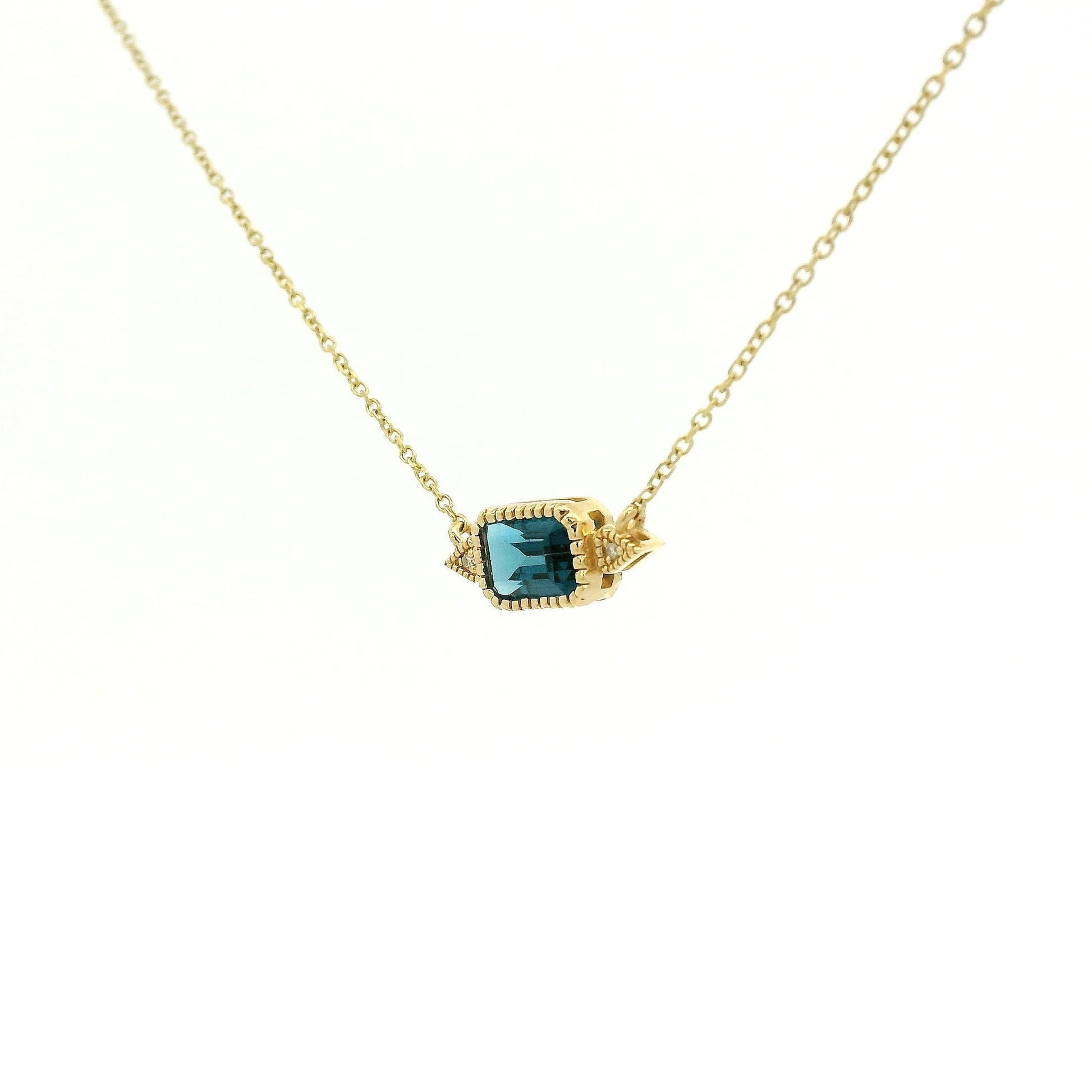 A Yellow Gold Pendant with a milgrain bezel set emerald cut natural London Blue Topaz in the center with 2 diamonds and a chain attached at Forever Rox Fine Jewelry, Lake Tahoes Best Jewelry Store