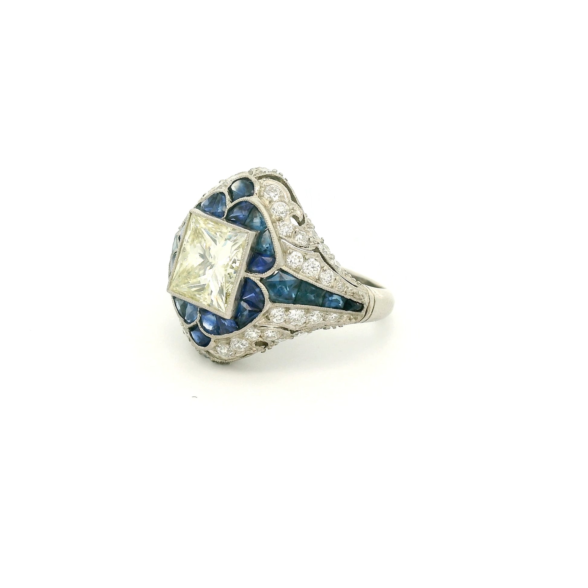 A Platinum Ring with a bezel set princess cut natural Diamond in the center with Sapphire and diamonds all around the ring at Forever Rox Fine Jewelry, Lake Tahoes Best Jewelry Store