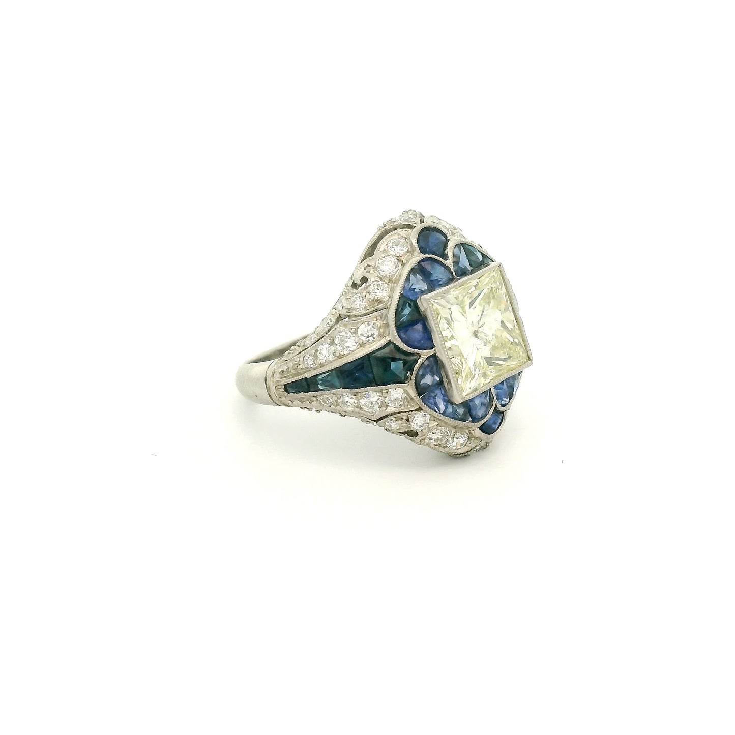 A Platinum Ring with a bezel set princess cut natural Diamond in the center with Sapphire and diamonds all around the ring at Forever Rox Fine Jewelry, Lake Tahoes Best Jewelry Store