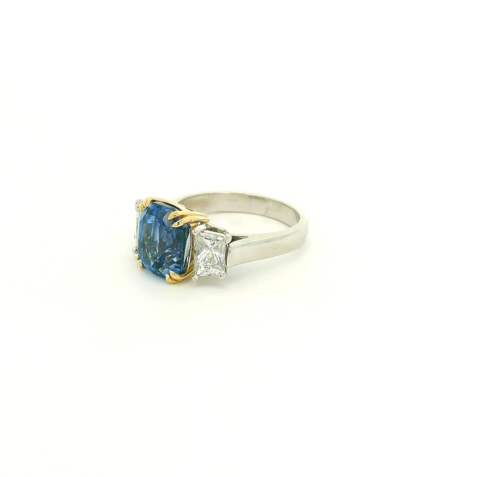 A Platinum & Yellow Gold Ring with a prong set natural TGC Certified No Heat Cushion Cut Cornflower Blue Sapphire & 2 Trapazoid Cut Diamonds at Forever Rox Fine Jewelry, Lake Tahoes Best Jewelry Store