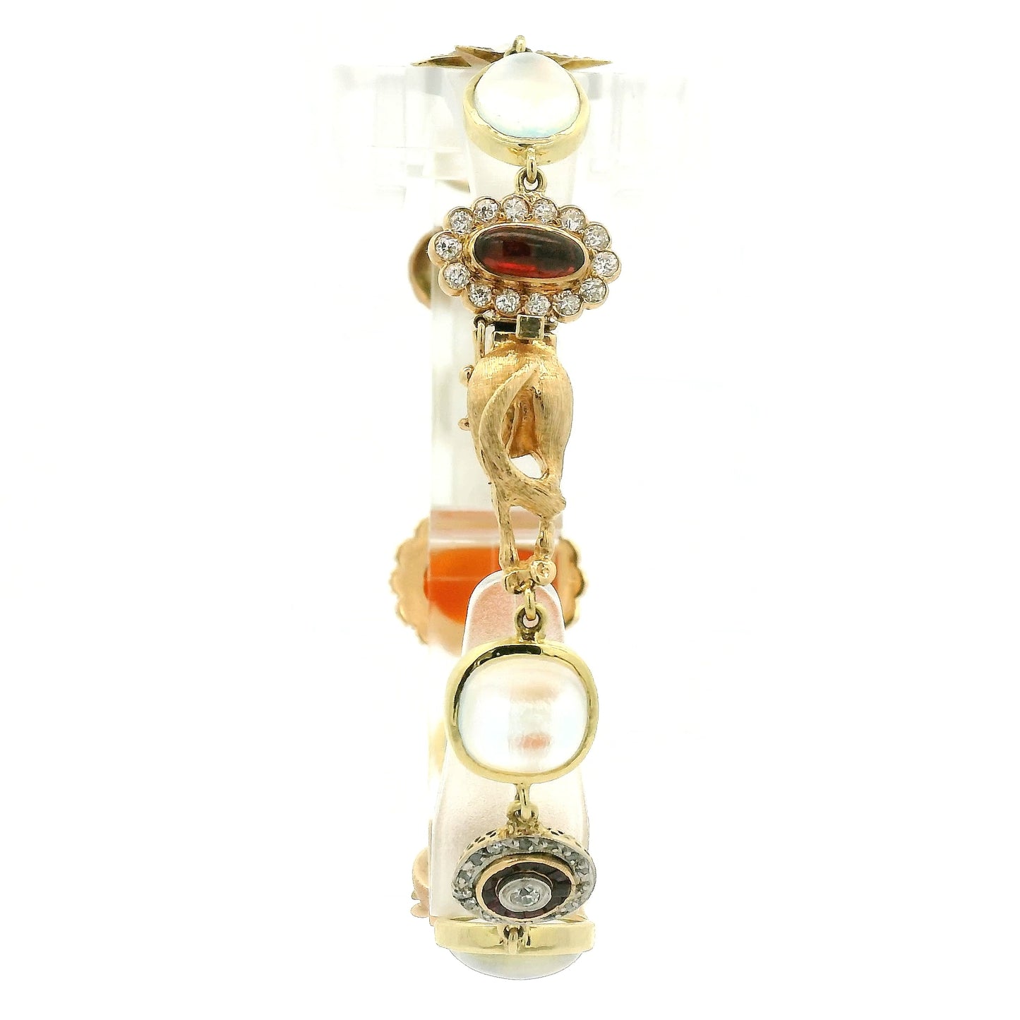 A vintage gold bracelet featuring a central orange carved shell cameo surrounded by small moonstones, with other gold links and stones at Forever Rox Fine Jewelry, Lake Tahoes Best Jewelry Store