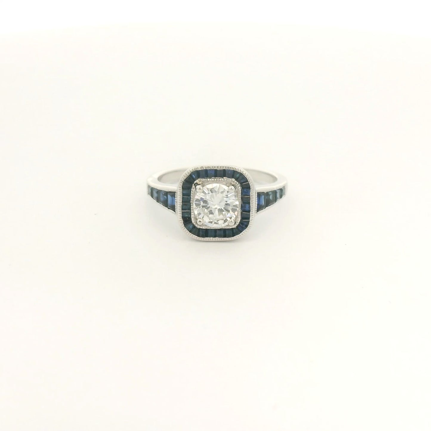A White Gold Ring with a prong set round cut natural Diamond in the center with a halo of baguette cut blue sapphires and sapphires down shank at Forever Rox Fine Jewelry, Lake Tahoes Best Jewelry Store
