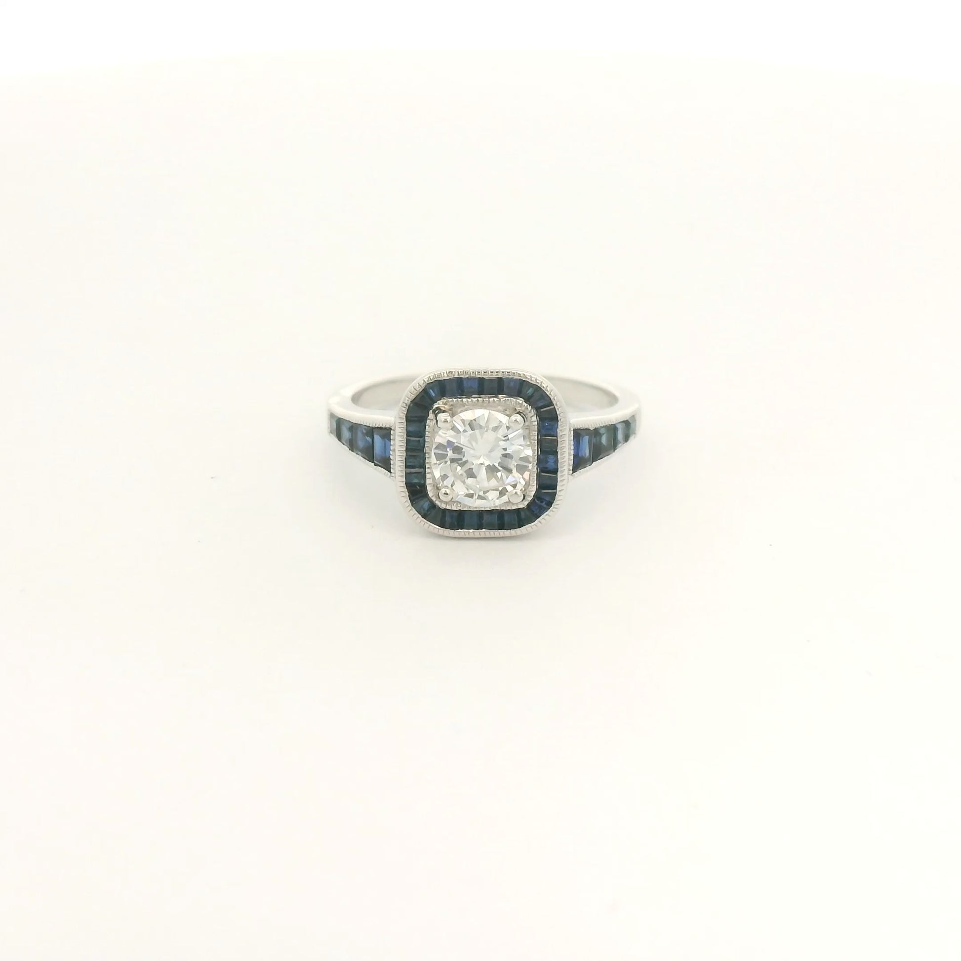 A White Gold Ring with a prong set round cut natural Diamond in the center with a halo of baguette cut blue sapphires and sapphires down shank at Forever Rox Fine Jewelry, Lake Tahoes Best Jewelry Store
