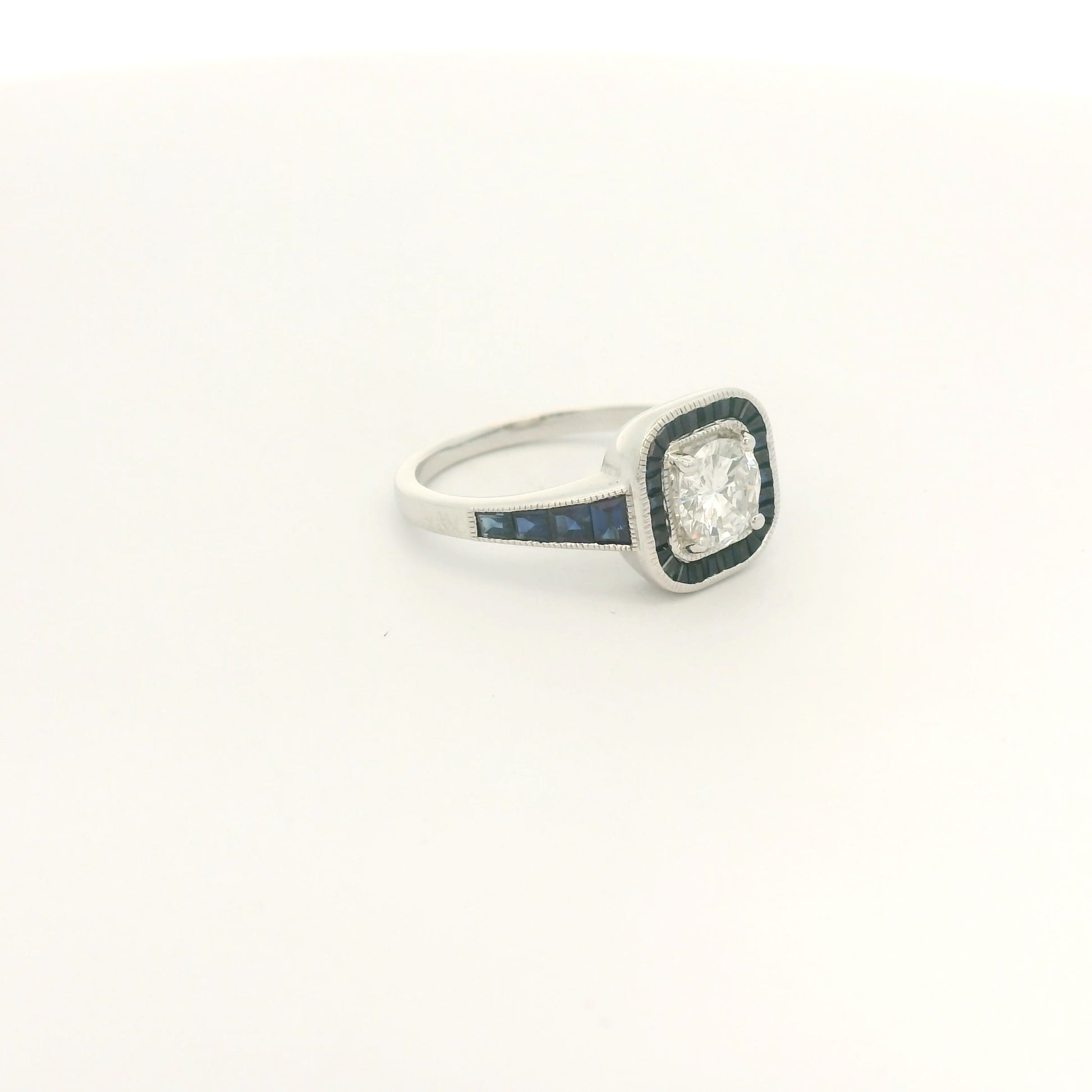 A White Gold Ring with a prong set round cut natural Diamond in the center with a halo of baguette cut blue sapphires and sapphires down shank at Forever Rox Fine Jewelry, Lake Tahoes Best Jewelry Store
