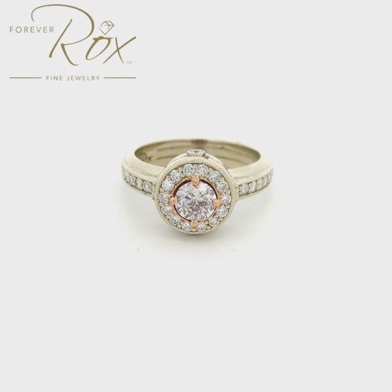 Custom Two Tone Ring with a round cut fancy pink diamond in the center with a diamond halo, diamonds down the shank and diamonds on the face of the head at Forever Rox Fine Jewelry