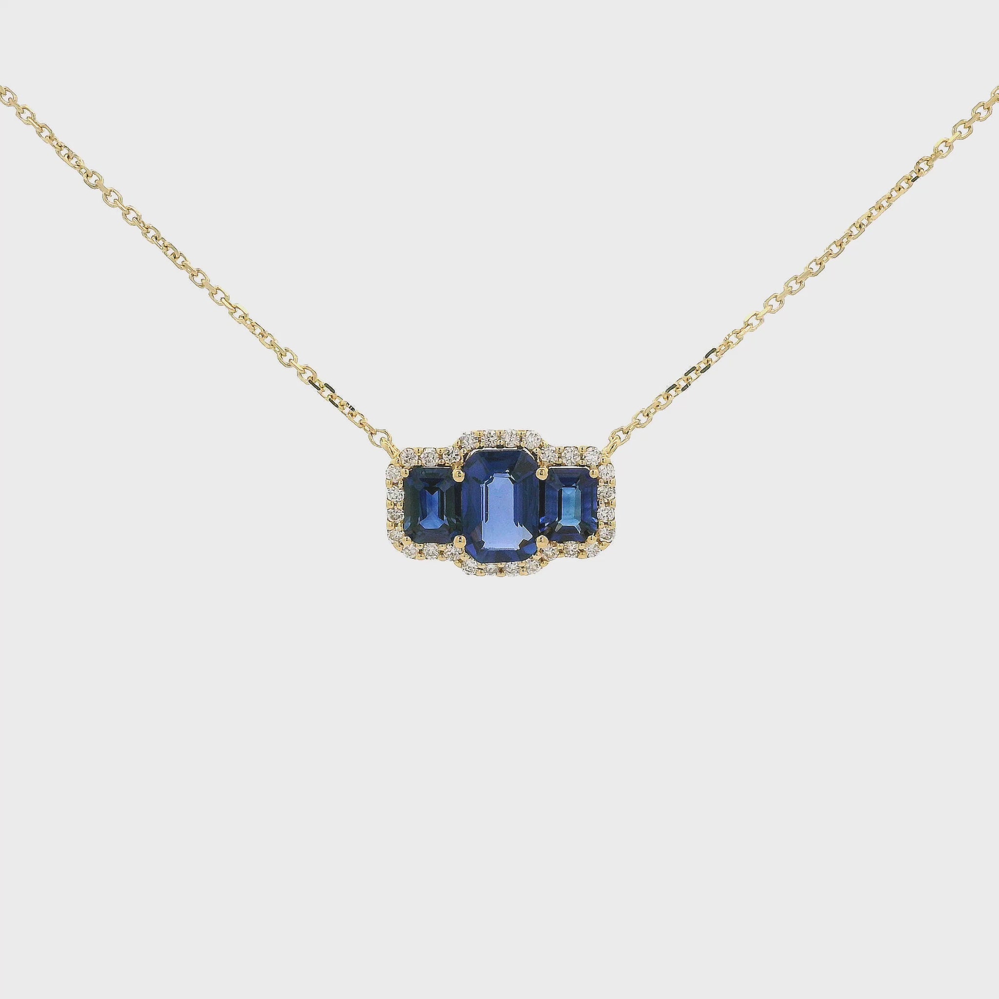 A Yellow Gold Pendant with three emerald cut natural Sapphires in the center with a halo of diamonds at Forever Rox Fine Jewelry, Lake Tahoes Best Jewelry Store
