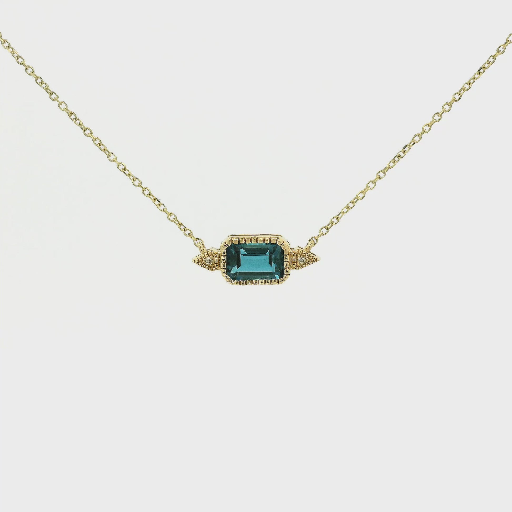 A Yellow Gold Pendant with a milgrain bezel set emerald cut natural London Blue Topaz in the center with 2 diamonds and a chain attached at Forever Rox Fine Jewelry, Lake Tahoes Best Jewelry Store
