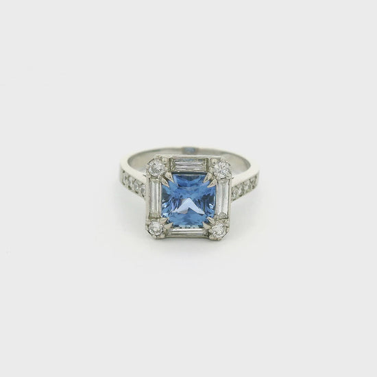 A Platinum Ring with a prong set square cushion cut blue Ceylonese Sapphire in the center with four baguette and four round cut diamonds around it with four round cut diamonds down each side of the shank at Forever Rox Fine Jewelry, Lake Tahoes Best Jewelry Store