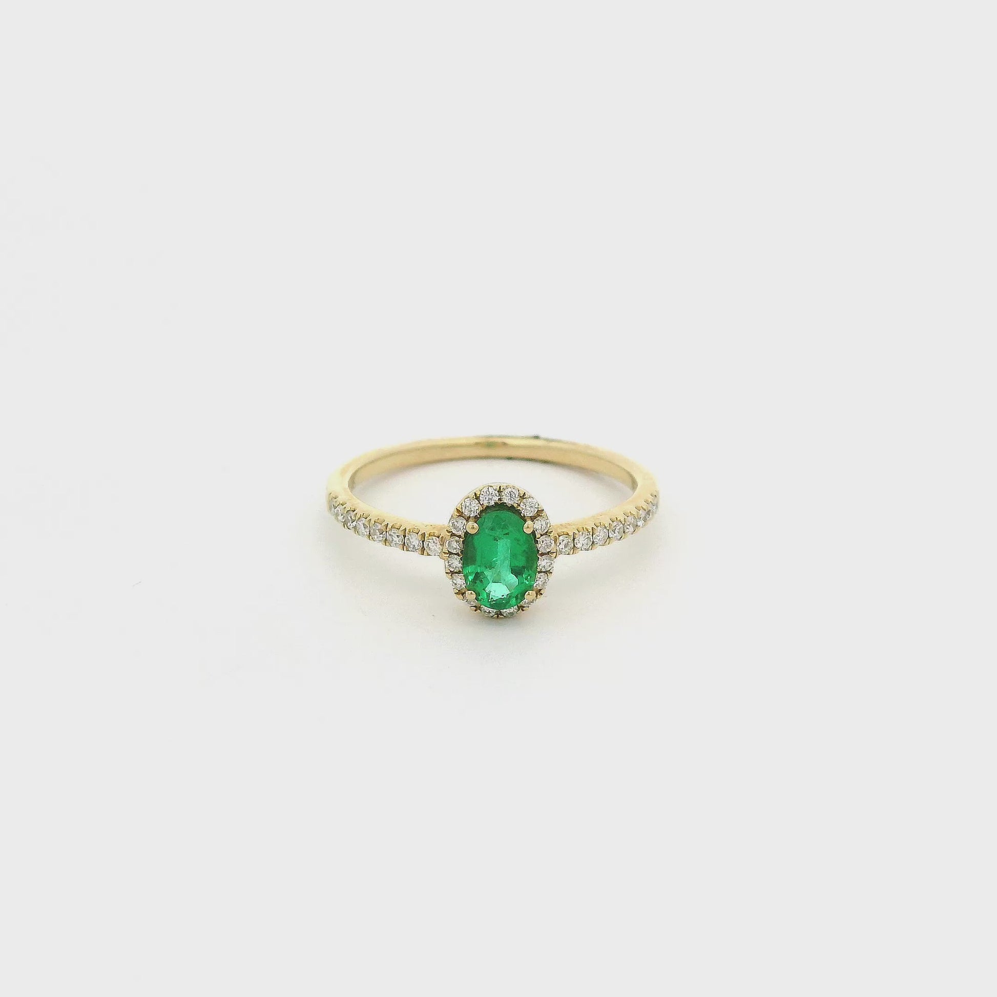 A Yellow Gold Ring with a prong set oval cut Emerald in the center with a diamond halo & diamonds down the shank at Forever Rox Fine Jewelry, Lake Tahoes Best Jewelry Store