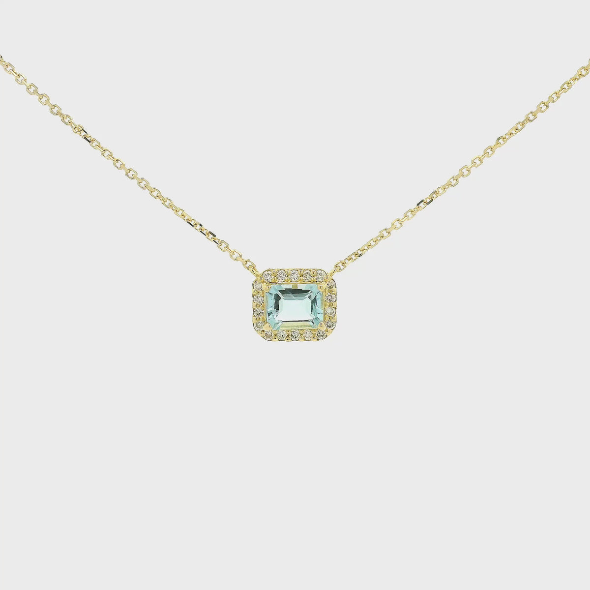 A Yellow Gold Pendant with a prong set emerald cut natural Aquamarine in the center with a diamond halo at Forever Rox Fine Jewelry, Lake Tahoes Best Jewelry Store
