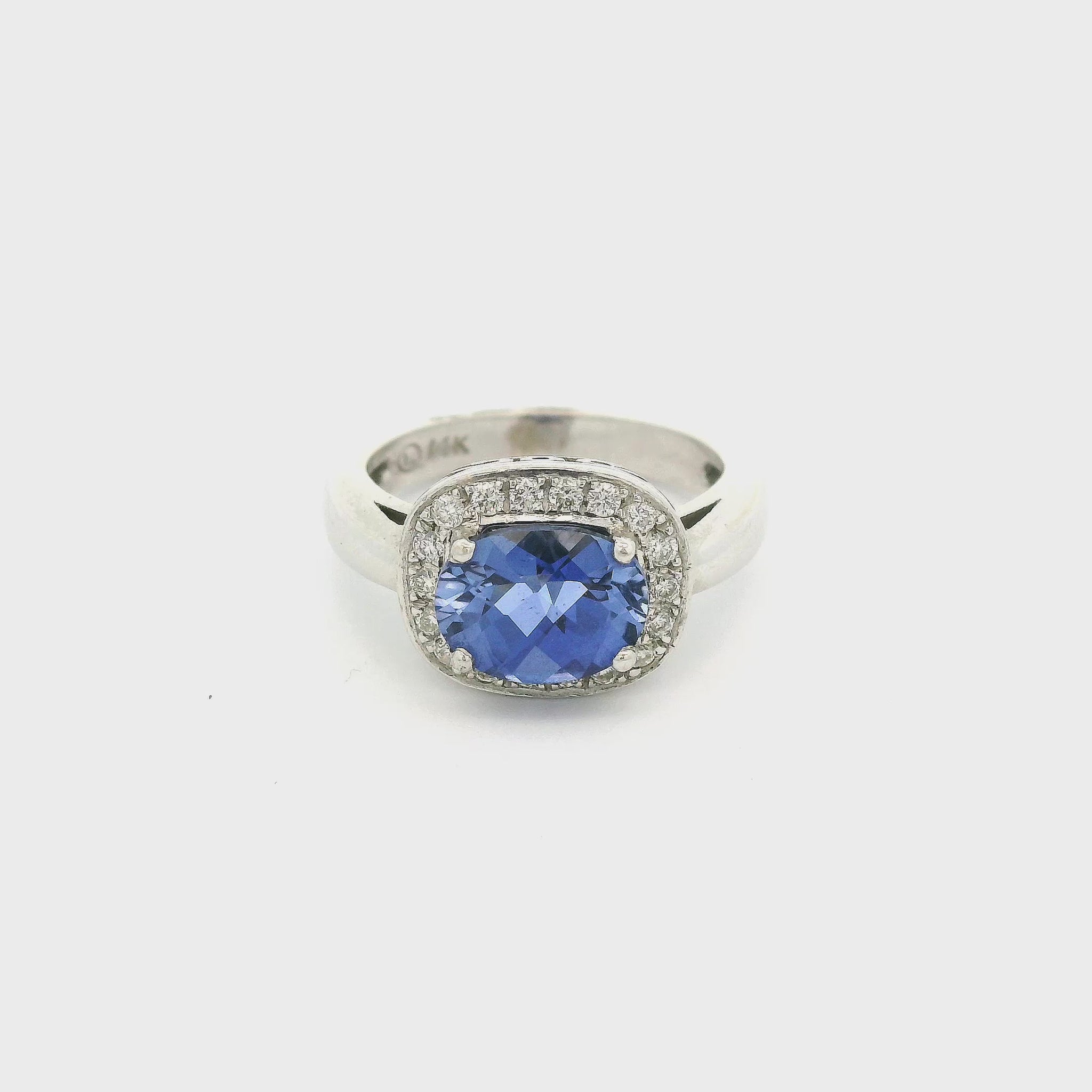 A Custom White Gold Ring with a prong set oval checkered board cut natural Tanzanite in the center with a halo of diamonds around it at Forever Rox Fine Jewelry, Lake Tahoes Best Jewelry Store