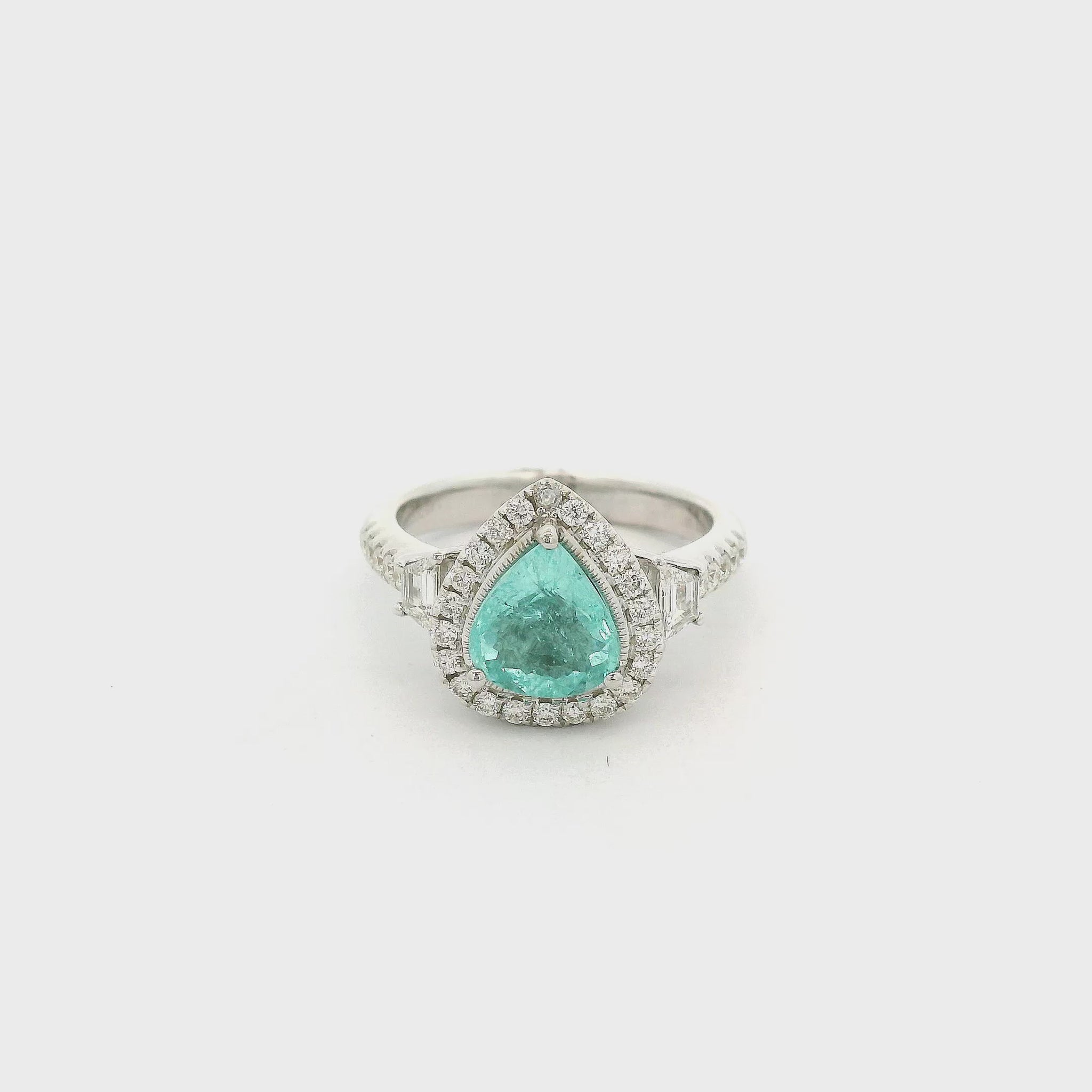 A White Gold Ring with a prong set pear cut natural Paraíba Tourmaline in the center with a halo of round cut diamonds and two trapazoid cut diamonds at Forever Rox Fine Jewelry, Lake Tahoes Best Jewelry Store