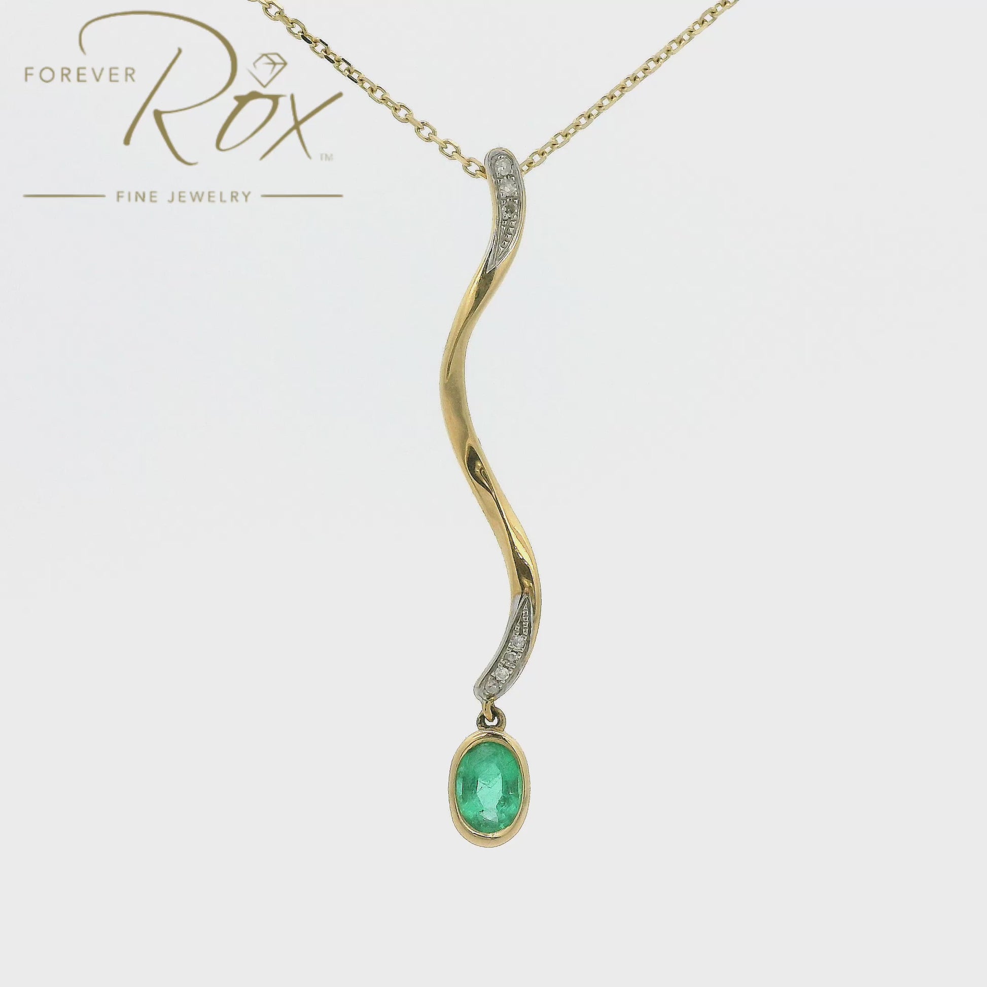 A Yellow Gold Pendant with a bezel set oval cut Emerald dangling at the bottom of a snake design pendant with diamonds at Forever Rox Fine Jewelry, Lake Tahoes Best Jewelry Store