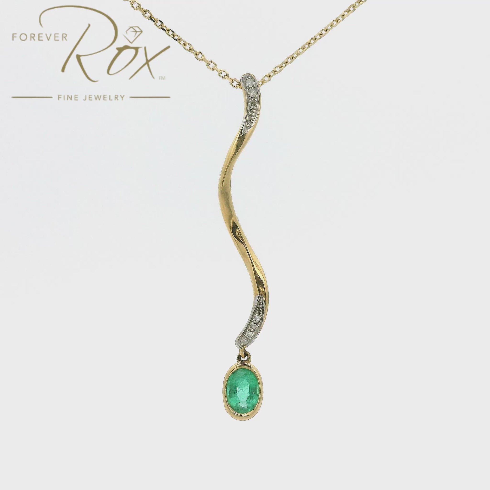 A Yellow Gold Pendant with a bezel set oval cut Emerald dangling at the bottom of a snake design pendant with diamonds at Forever Rox Fine Jewelry, Lake Tahoes Best Jewelry Store