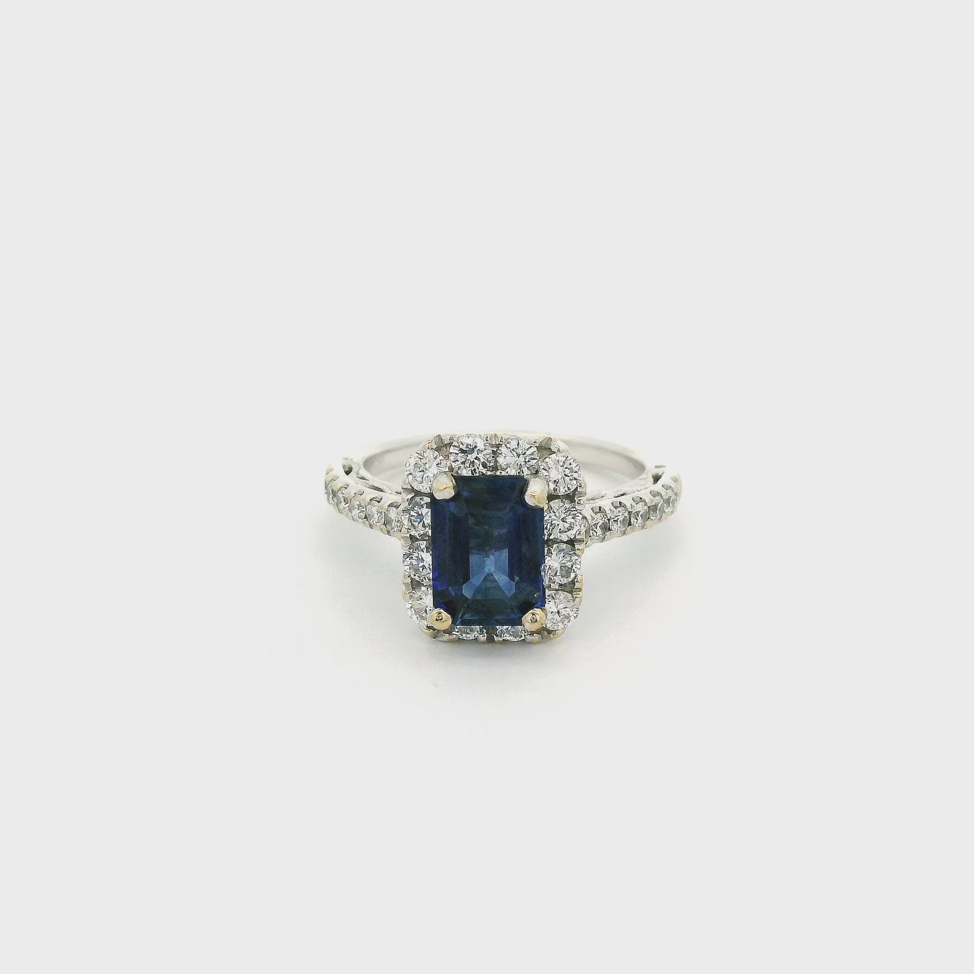 A White Gold Ring with a prong set emerald cut natural Sapphire in the center with a halo of diamonds and diamonds down the shank at Forever Rox Fine Jewelry, Lake Tahoes Best Jewelry Store

