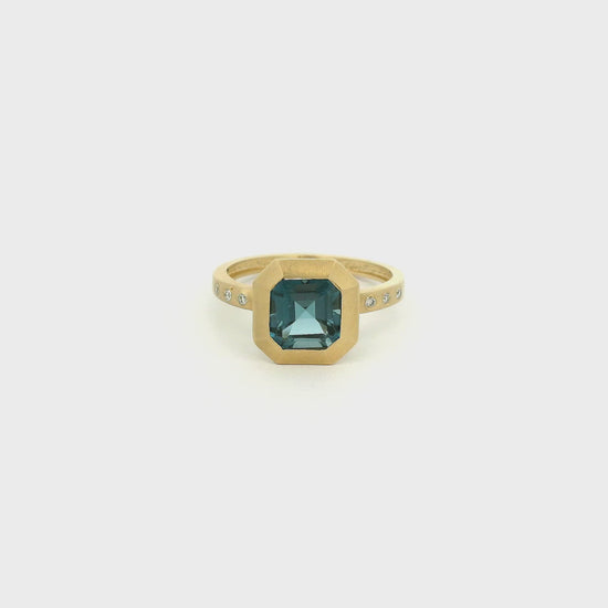 A Yellow Gold Ring with a bezel set square merald cut cut natural London Blue Topaz in the center with flush set diamonds in the band at Forever Rox Fine Jewelry, Lake Tahoes Best Jewelry Store
