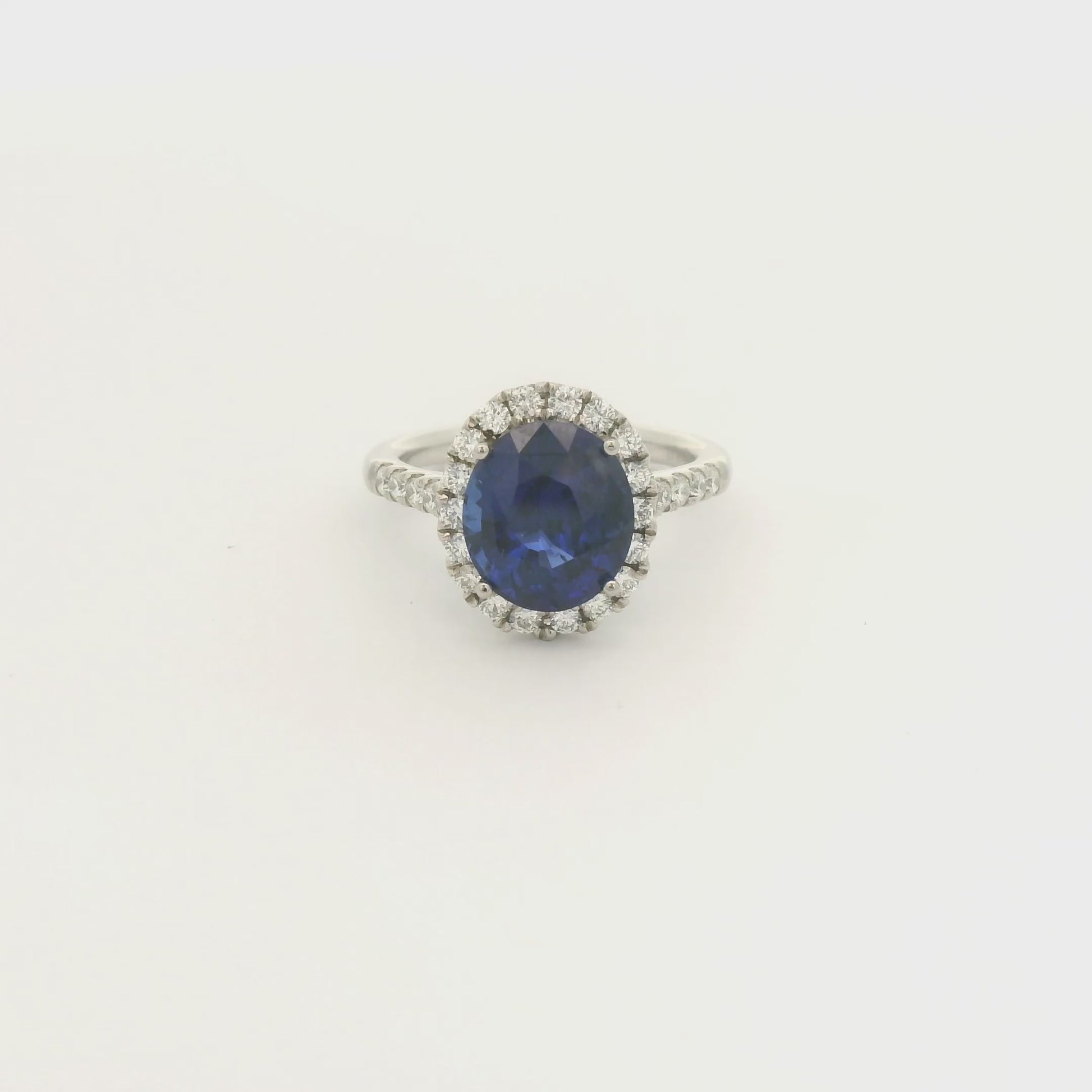 A Platinum Ring with a prong set oval cut natural Sapphire in the center with a diamond halo and diamonds down shank at Forever Rox Fine Jewelry, Lake Tahoes Best Jewelry Store
