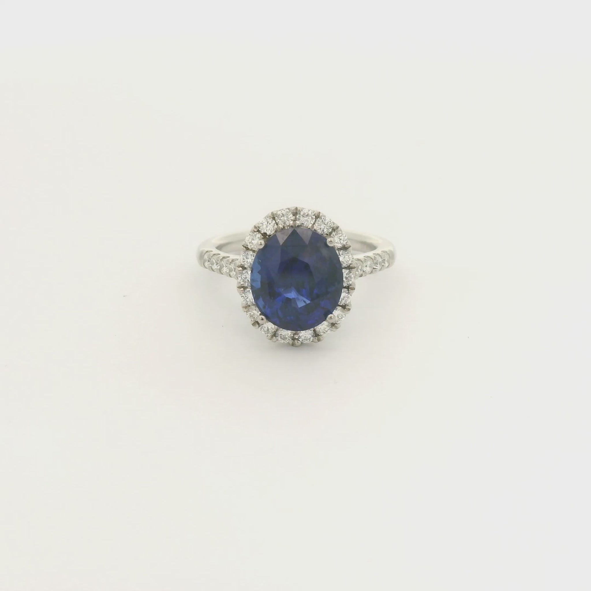 A Platinum Ring with a prong set oval cut natural Sapphire in the center with a diamond halo and diamonds down shank at Forever Rox Fine Jewelry, Lake Tahoes Best Jewelry Store