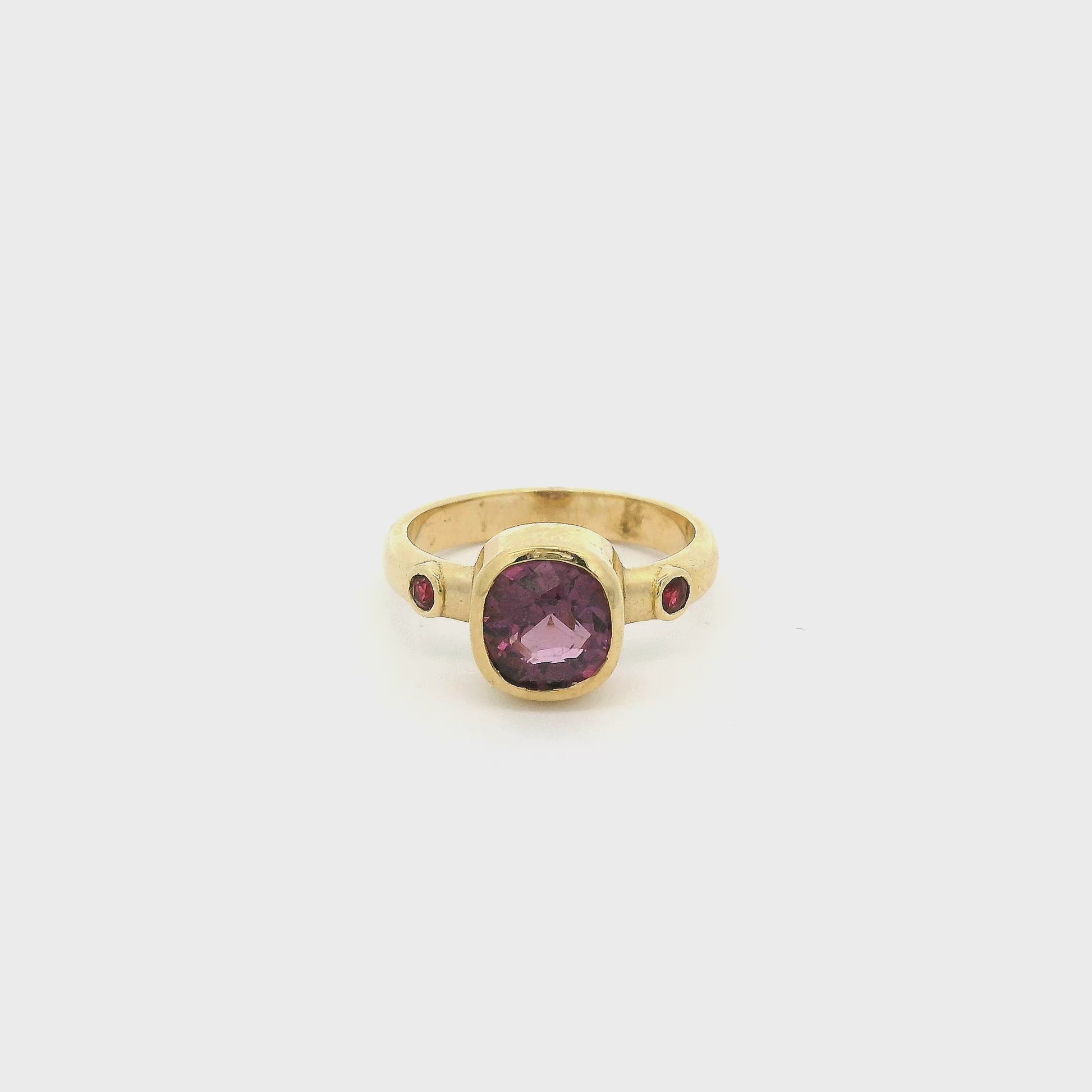 A Yellow Gold Ring with a bezel set cushion cut natural Lavender Spinel in the center with two bezel set rubies at Forever Rox Fine Jewelry, Lake Tahoes Best Jewelry Store