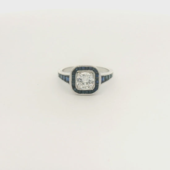 A White Gold Ring with a prong set round cut natural Diamond in the center with a halo of baguette cut blue sapphires and sapphires down shank at Forever Rox Fine Jewelry, Lake Tahoes Best Jewelry Store
