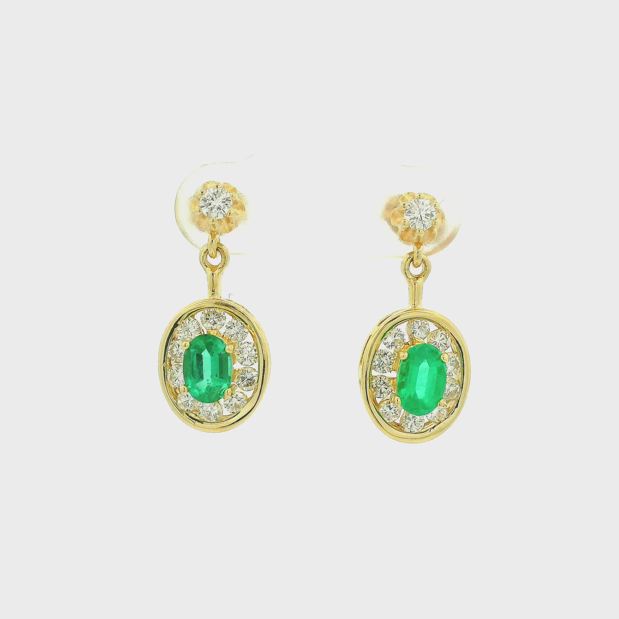 A Pair of Yellow Gold Dangle Earrings with prong set oval cut natural Emerald in the center with a channel set diamond halo at Forever Rox Fine Jewelry, Lake Tahoes Best Jewelry Store
