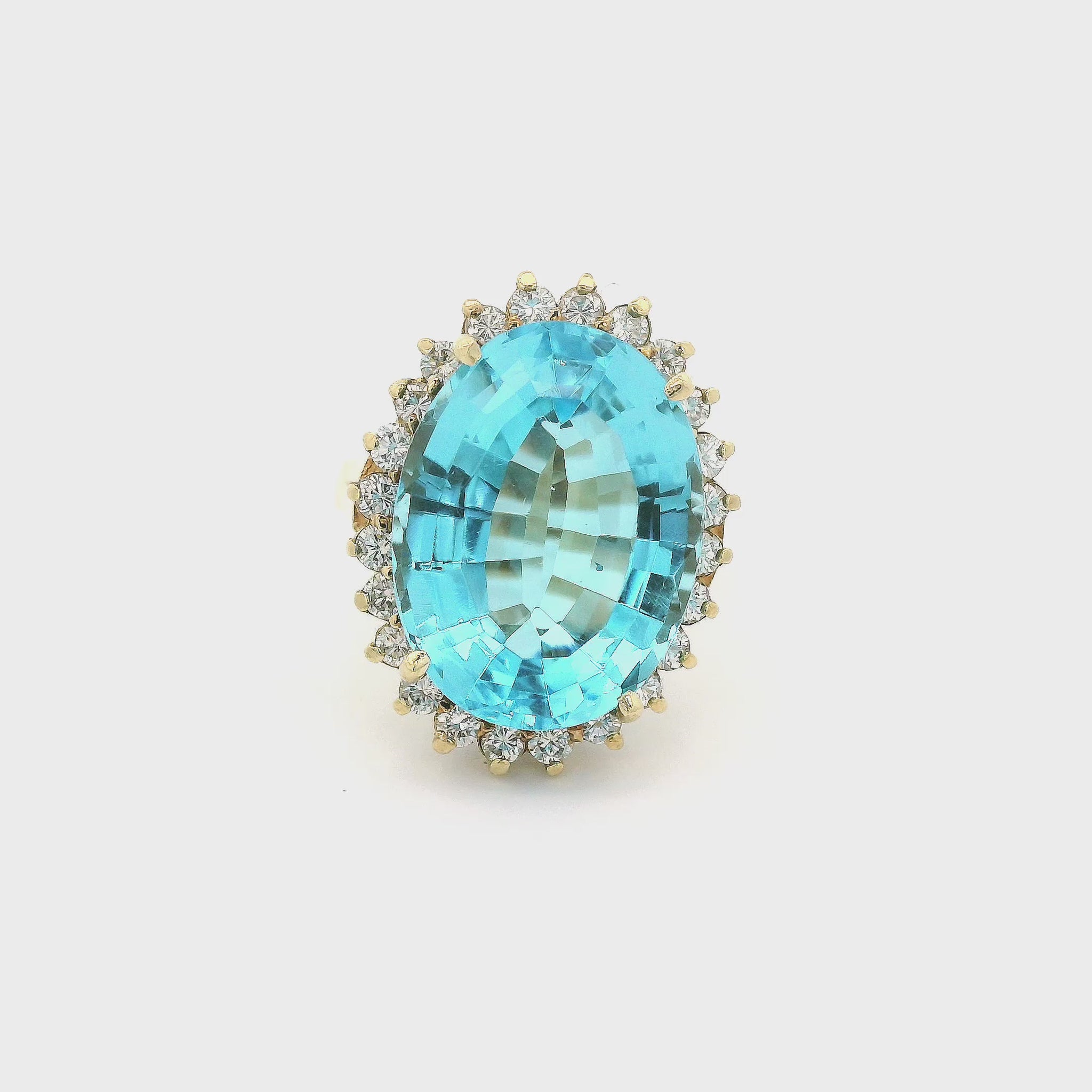 A Yellow Gold Coctail Ring with a prong set oval cut light blue Topaz in the center with a halo of diamonds around it at Forever Rox Fine Jewelry, Lake Tahoes Best Jewelry Store