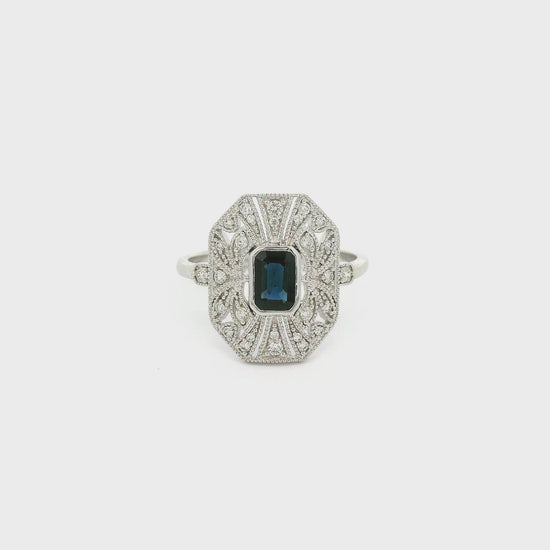 A White Gold Art Deco Style Ring with a bezel set emerald cut blue Sapphire in the center withdiamonds and milgrain design at Forever Rox Fine Jewelry, Lake Tahoes Best Jewelry Store