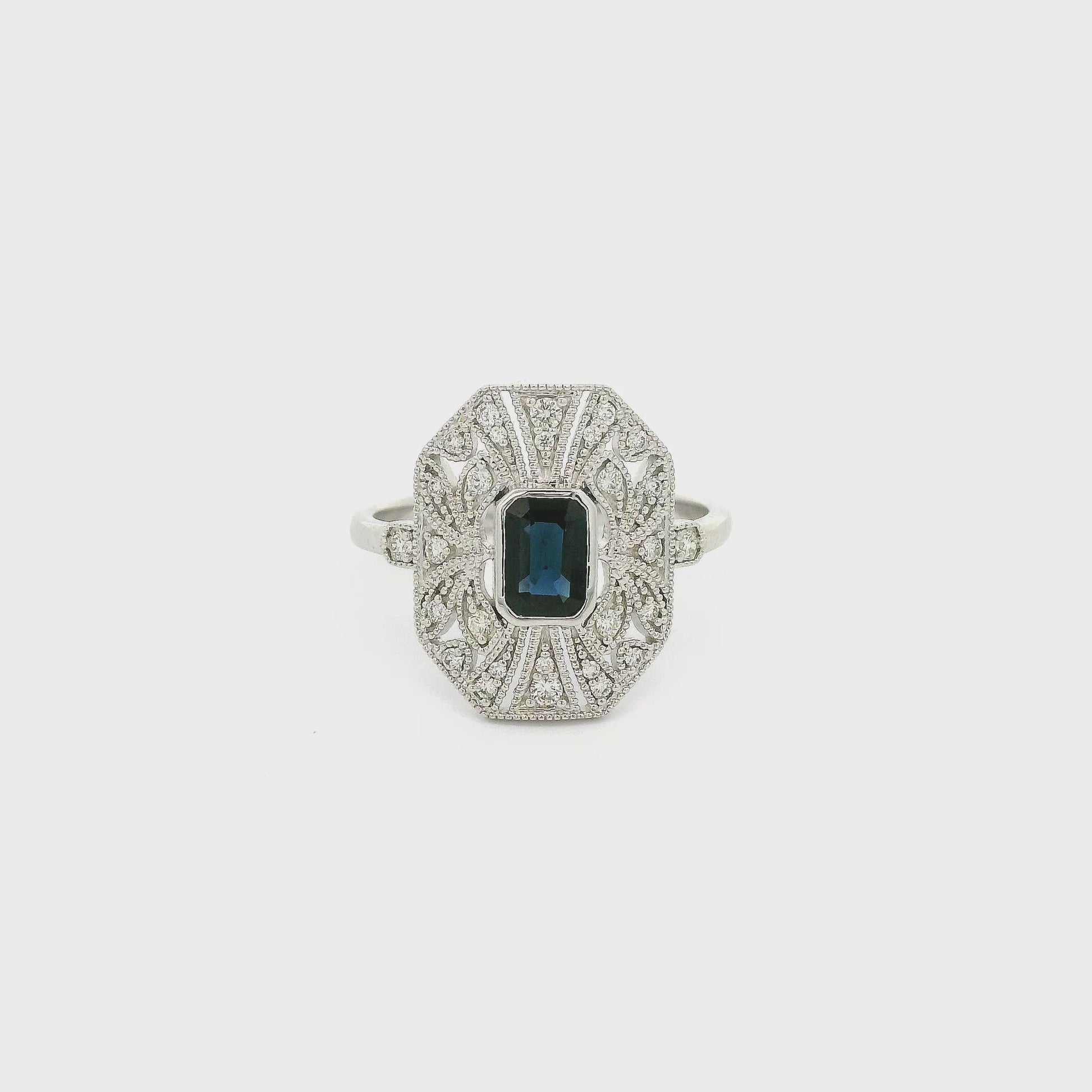A White Gold Art Deco Style Ring with a bezel set emerald cut blue Sapphire in the center withdiamonds and milgrain design at Forever Rox Fine Jewelry, Lake Tahoes Best Jewelry Store