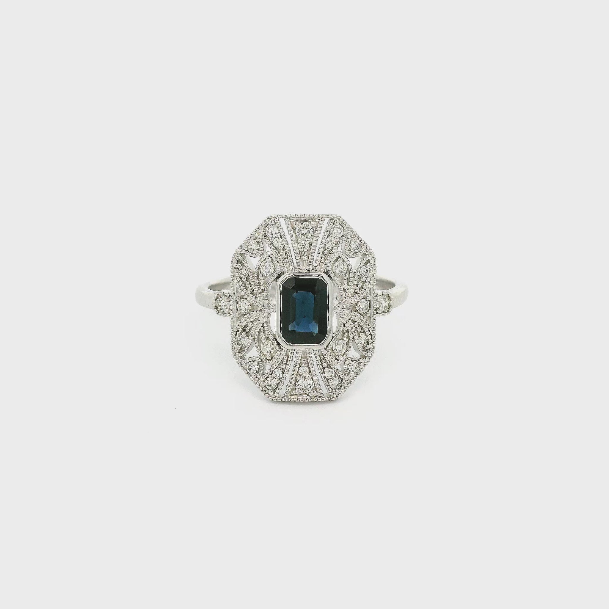 A White Gold Art Deco Style Ring with a bezel set emerald cut blue Sapphire in the center withdiamonds and milgrain design at Forever Rox Fine Jewelry, Lake Tahoes Best Jewelry Store