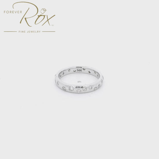 This custom flush-set diamond scatter band is crafted in 14k white gold and features brilliant round diamonds thoughtfully spaced around the band in a modern scattered design. The flush-set construction creates a sleek, low-profile look while allowing each diamond to sparkle from within the metal. Elegant, comfortable, and timeless, this custom piece is perfect as a wedding band, stacking ring, or everyday statement.
