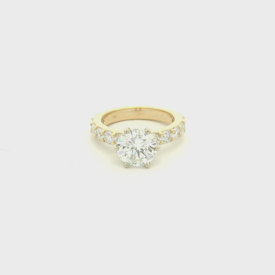 This custom 14k yellow gold engagement ring was designed around a client’s treasured diamond, creating a one-of-a-kind heirloom to be cherished for generations. The stunning 2.05 carat round brilliant cut natural diamond was professionally GIA graded as F color, VS1 clarity, and Excellent cut, polish, and symmetry (Triple Excellent) before being set into its custom-made mounting. Framing the center stone are 1.30 total carats of natural diamonds flowing down the substantial 3mm-wide band, adding brilliance 