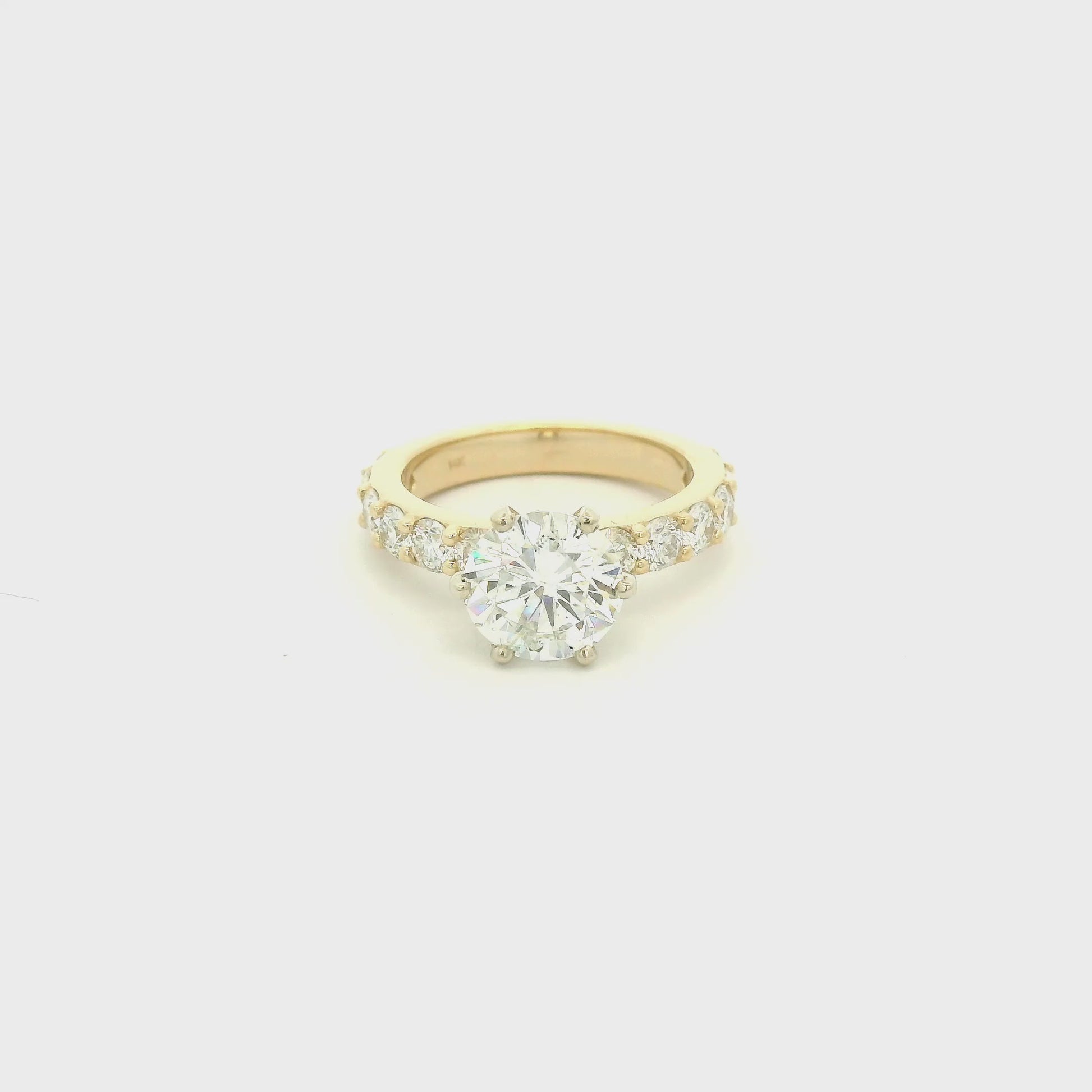 This custom 14k yellow gold engagement ring was designed around a client’s treasured diamond, creating a one-of-a-kind heirloom to be cherished for generations. The stunning 2.05 carat round brilliant cut natural diamond was professionally GIA graded as F color, VS1 clarity, and Excellent cut, polish, and symmetry (Triple Excellent) before being set into its custom-made mounting. Framing the center stone are 1.30 total carats of natural diamonds flowing down the substantial 3mm-wide band, adding brilliance 