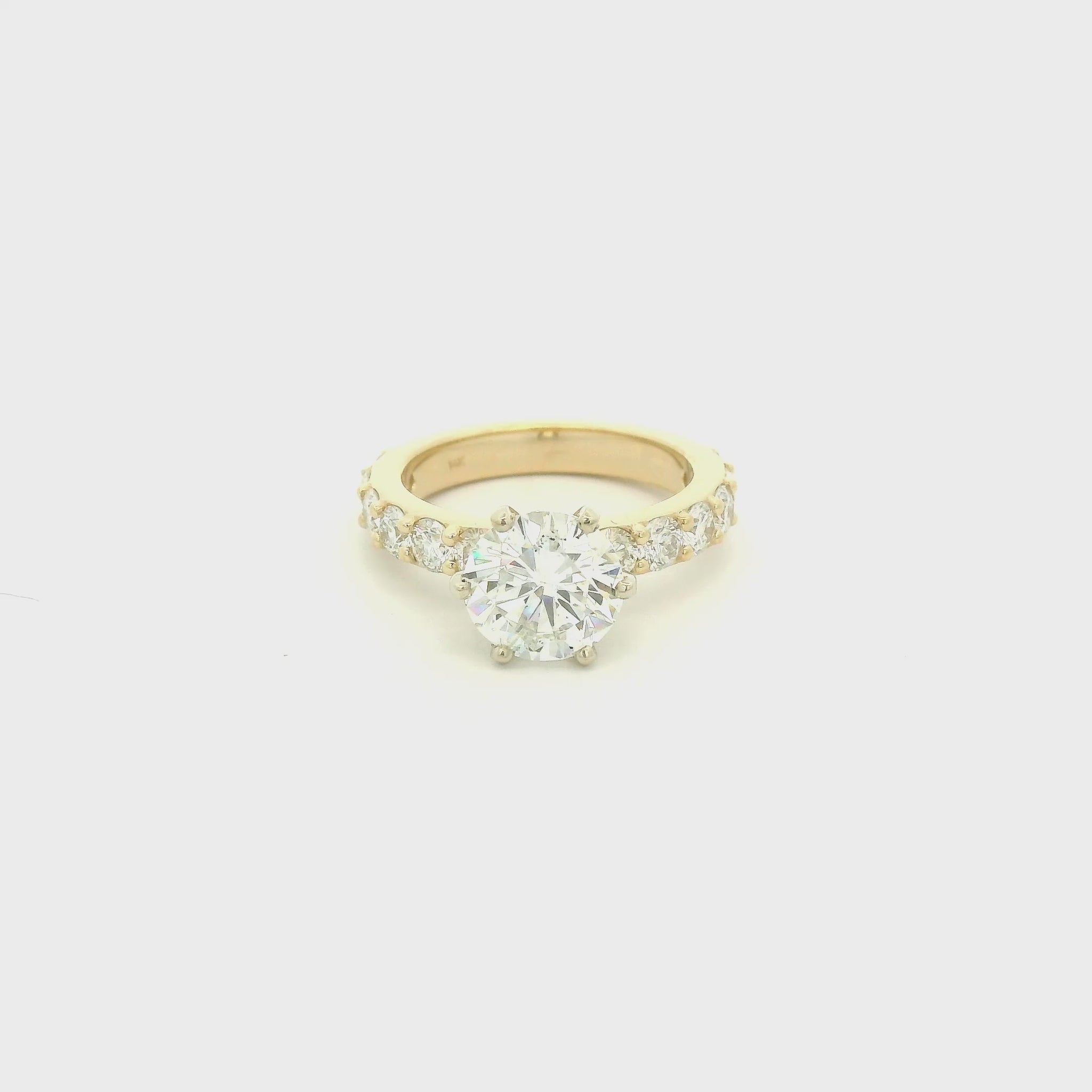 This custom 14k yellow gold engagement ring was designed around a client’s treasured diamond, creating a one-of-a-kind heirloom to be cherished for generations. The stunning 2.05 carat round brilliant cut natural diamond was professionally GIA graded as F color, VS1 clarity, and Excellent cut, polish, and symmetry (Triple Excellent) before being set into its custom-made mounting. Framing the center stone are 1.30 total carats of natural diamonds flowing down the substantial 3mm-wide band, adding brilliance 