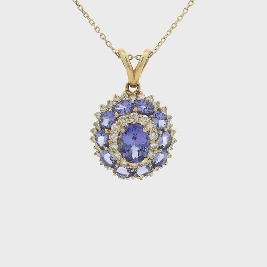A Yellow Gold Pendant with a prong set oval cut natural Tanzanite in the center a halo of diamonds then a halo of 10 tanzanites and another halo of diamonds Forever Rox Fine Jewelry, Lake Tahoes Best Jewelry Store