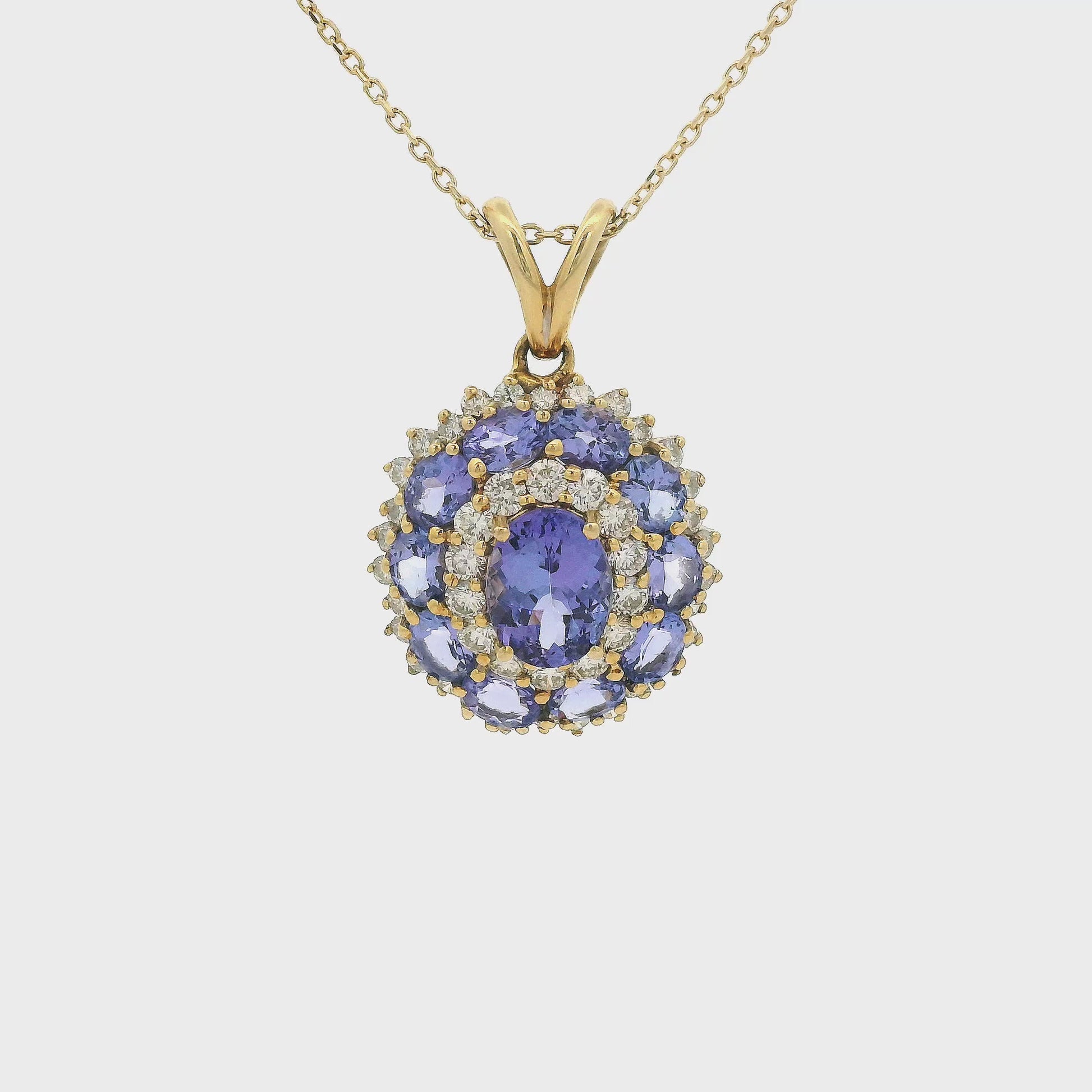 A Yellow Gold Pendant with a prong set oval cut natural Tanzanite in the center a halo of diamonds then a halo of 10 tanzanites and another halo of diamonds Forever Rox Fine Jewelry, Lake Tahoes Best Jewelry Store