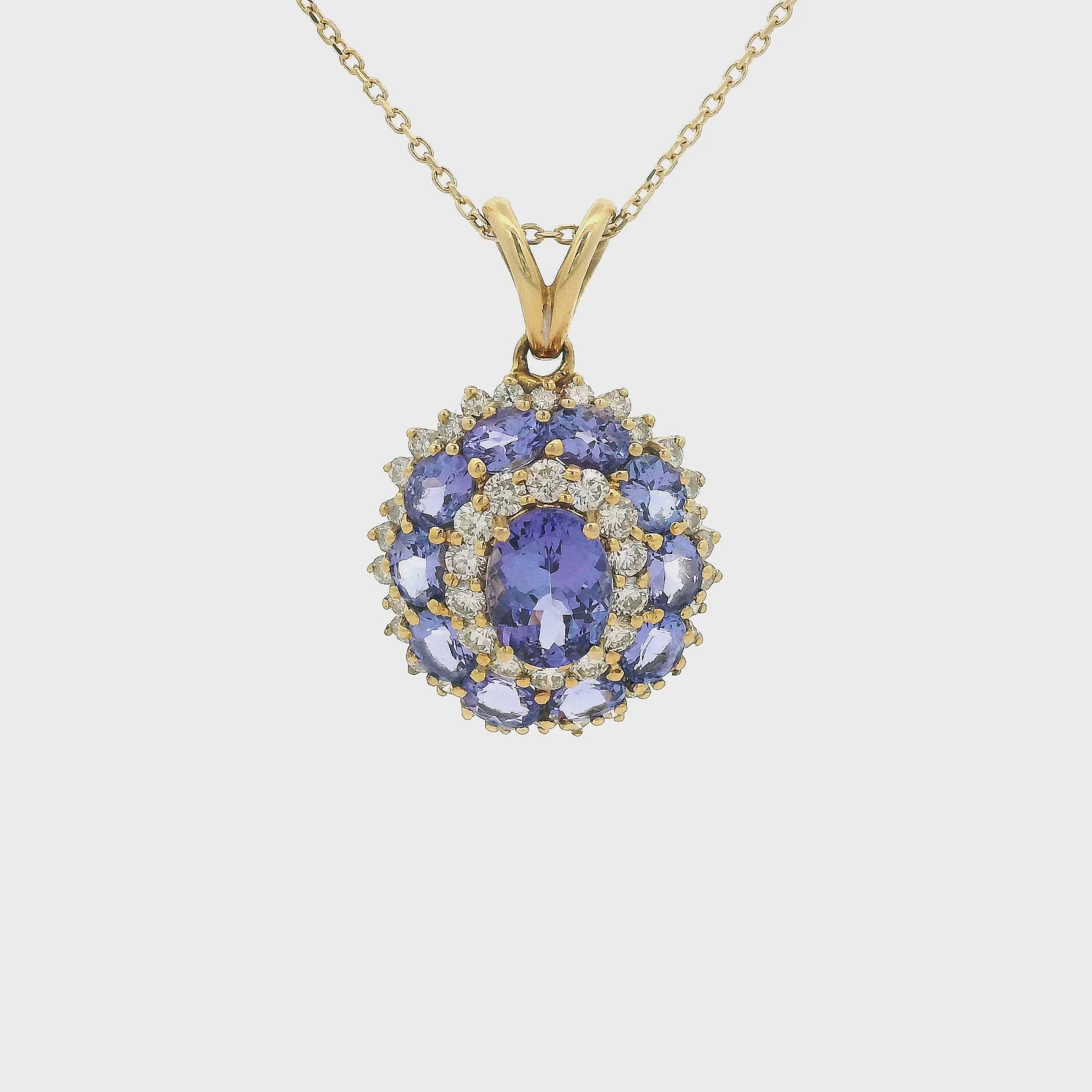 A Yellow Gold Pendant with a prong set oval cut natural Tanzanite in the center a halo of diamonds then a halo of 10 tanzanites and another halo of diamonds Forever Rox Fine Jewelry, Lake Tahoes Best Jewelry Store