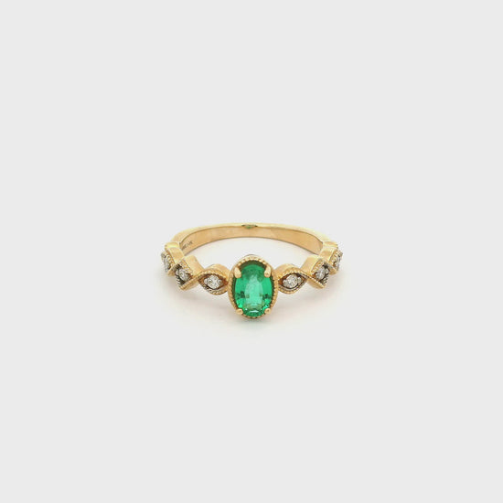 A Yellow Gold Ring with a prong set oval cut Emerald in the center with three diamonds down each side in milgrain different shape bezels at Forever Rox Fine Jewelry, Lake Tahoes Best Jewelry Store