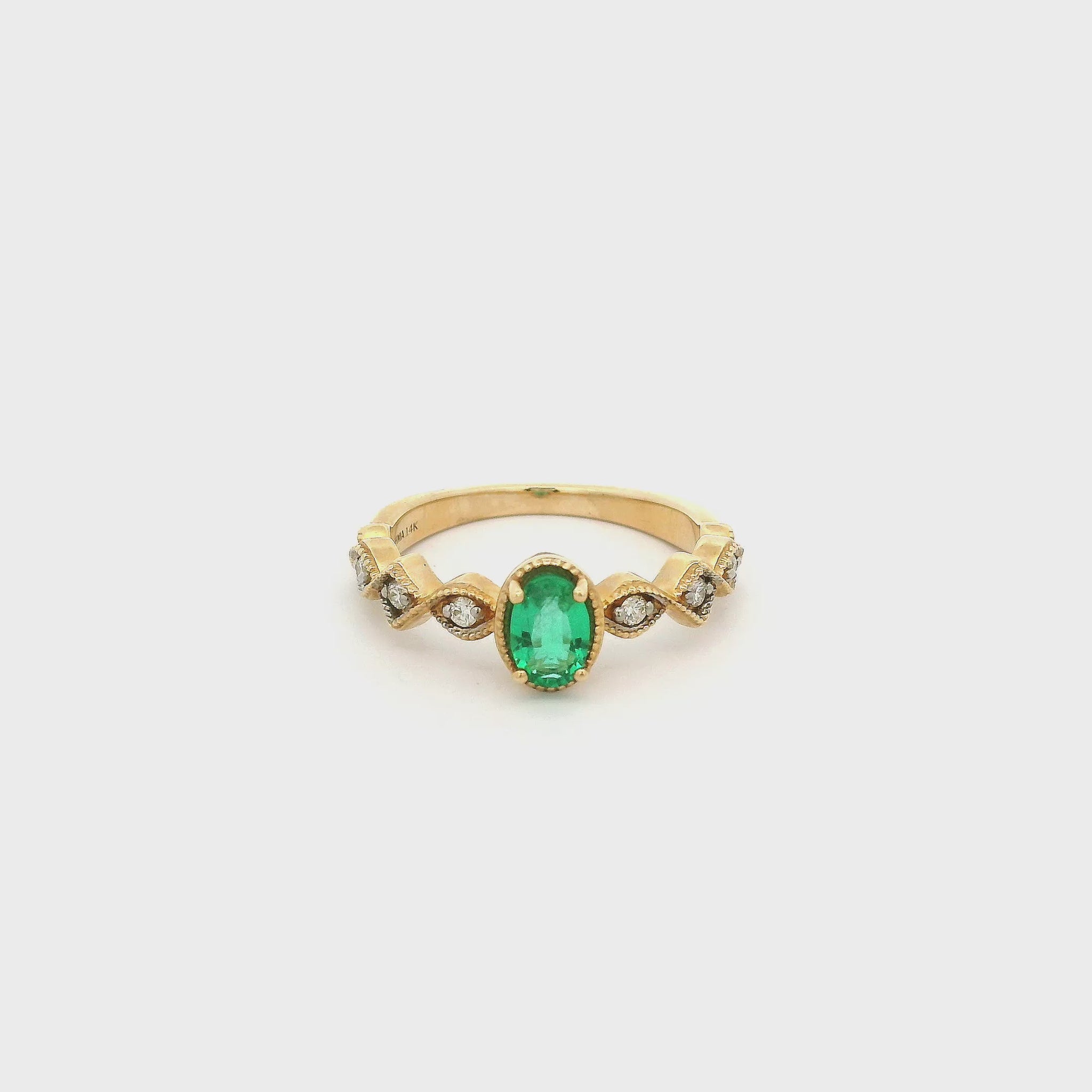 A Yellow Gold Ring with a prong set oval cut Emerald in the center with three diamonds down each side in milgrain different shape bezels at Forever Rox Fine Jewelry, Lake Tahoes Best Jewelry Store